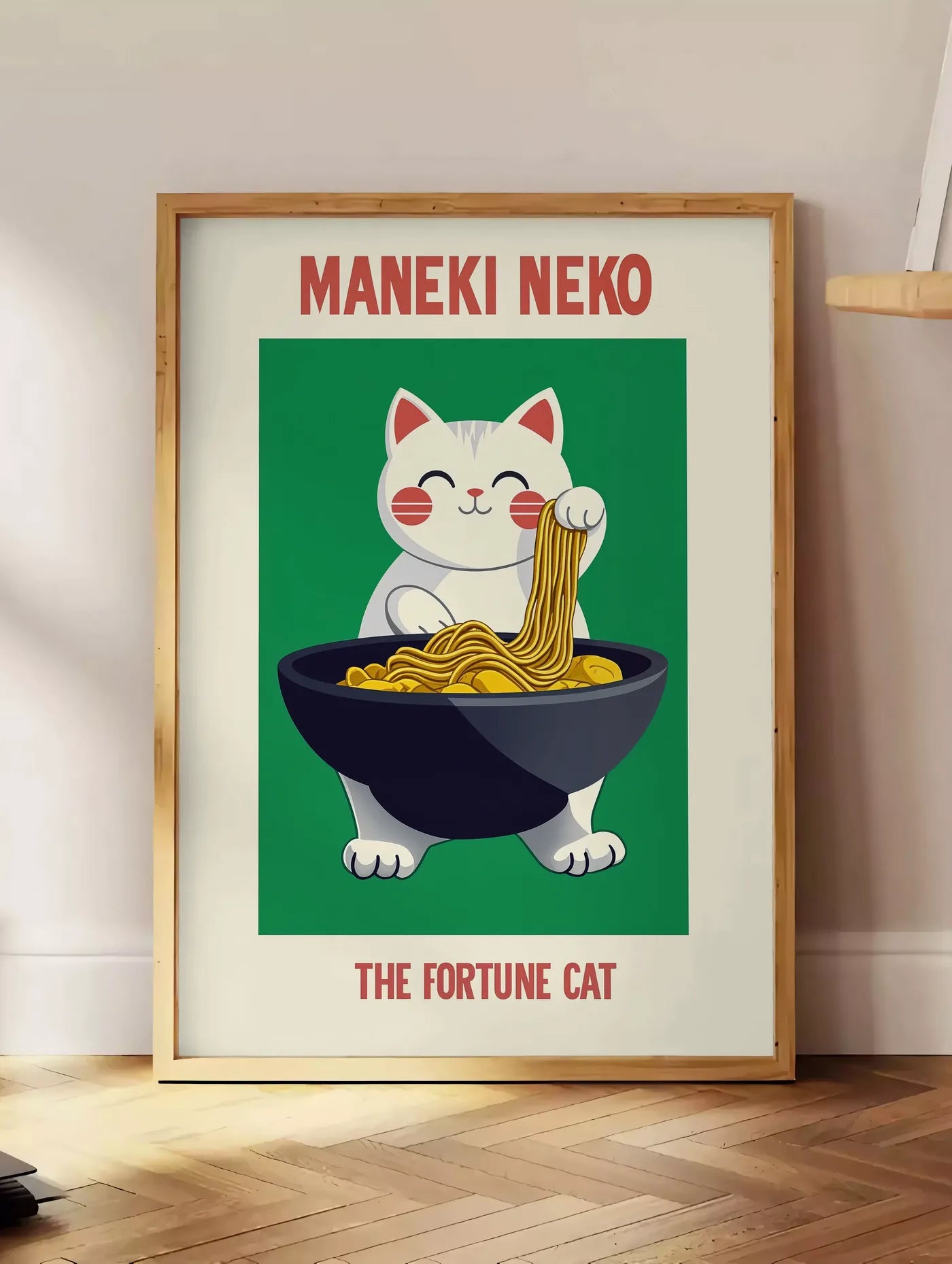 Estampe affiche Maneki Neko chat porte-bonheur attrapant des ramen au-dessus d'un bol noir, posee au sol dans un coin salon, sur un parquet a chevrons, pres d'une table d'appoint en chene chargee de livres