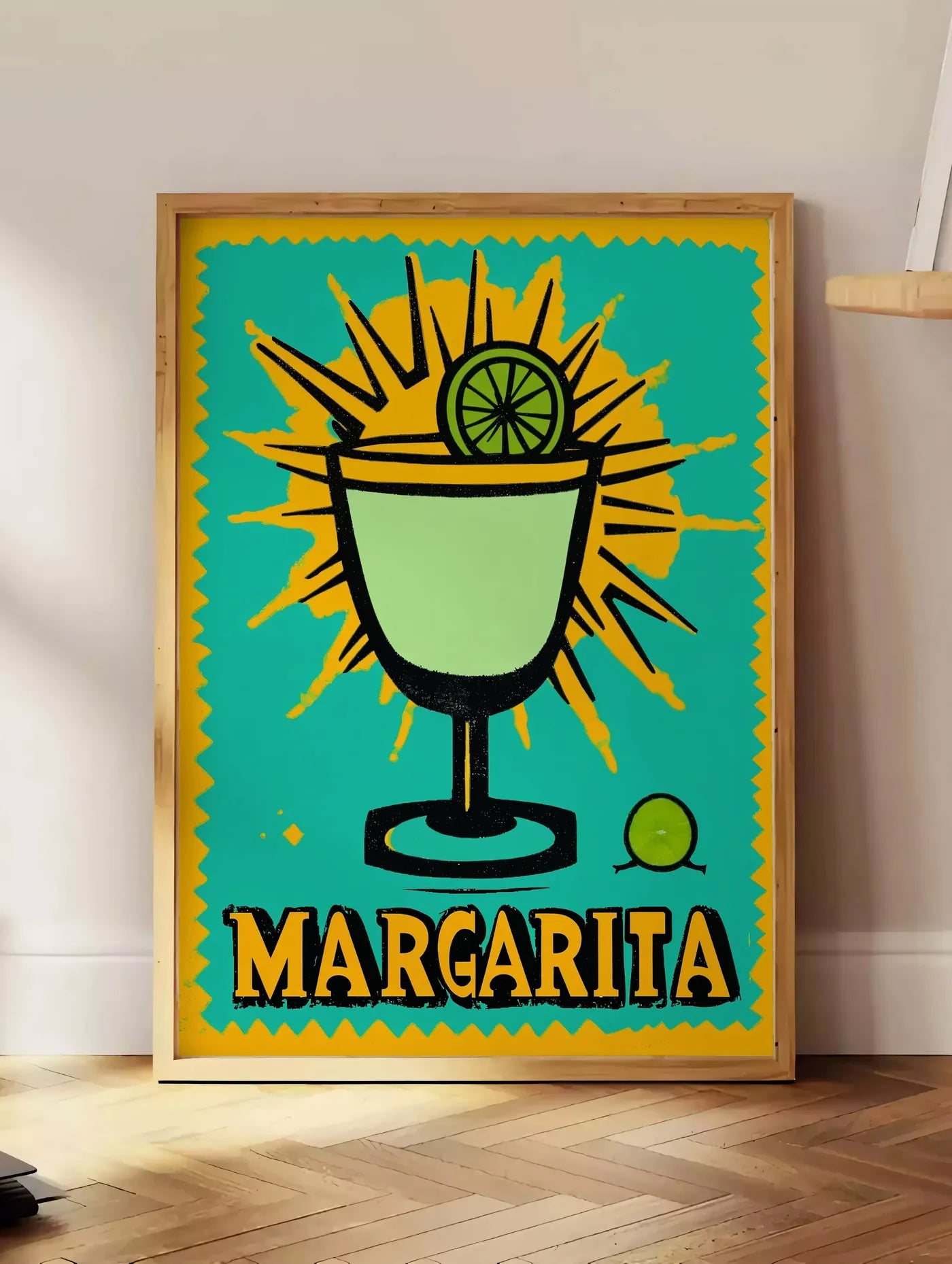 Estampe affiche cocktail Margarita pop art, posee au sol dans un coin salon, sur un parquet a chevrons, pres d'une table d'appoint en chene chargee de livres