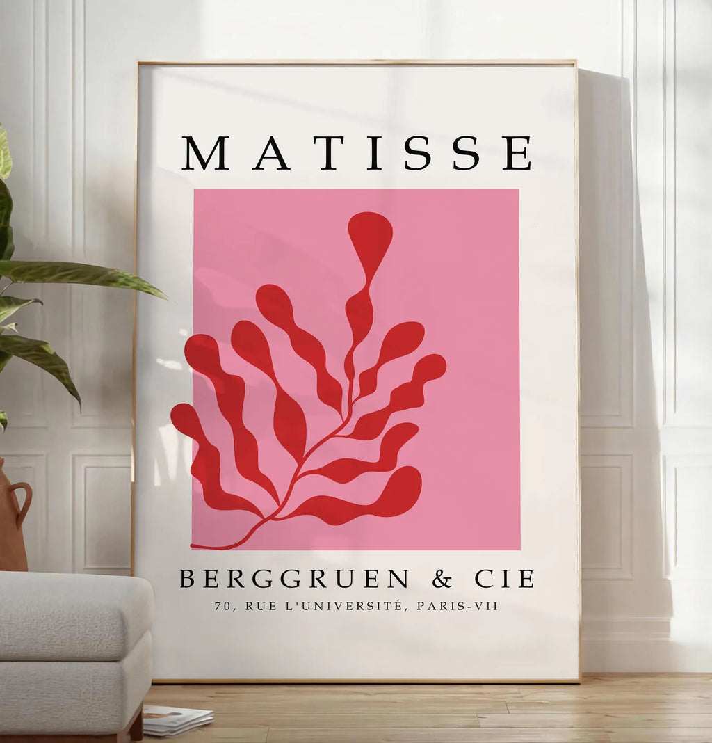Reproduction algue Rouge sur Rose en papiers decoupes Matisse sur fond colore, posee au sol dans un salon minimaliste clair, a cote d'un canape beige et d'une plante verte, sur un parquet clair