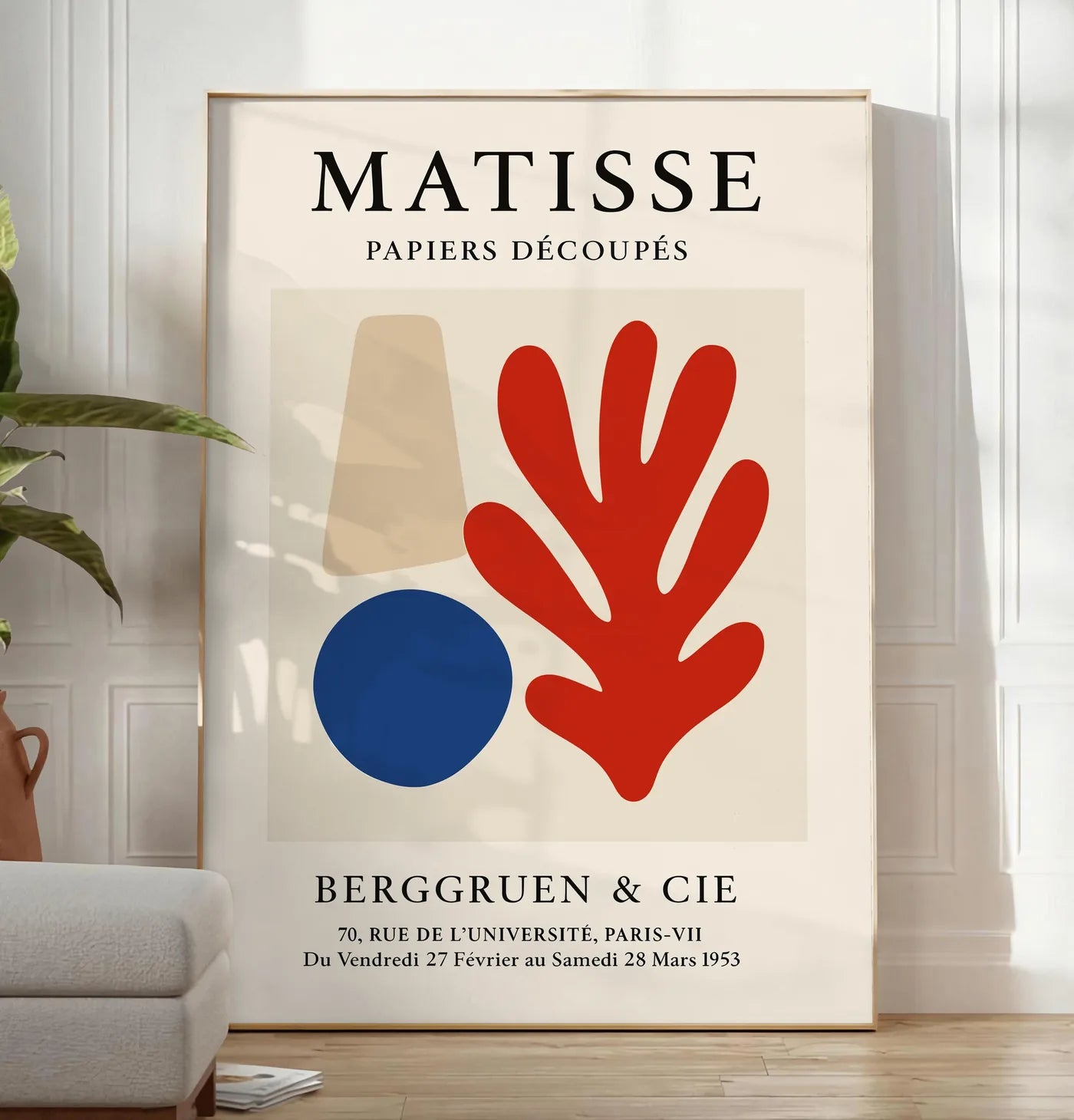 Reproduction cone beige cercle bleu et corail rouge sur fond creme, posee au sol dans un salon minimaliste clair, a cote d'un canape beige et d'une plante verte, sur un parquet clair