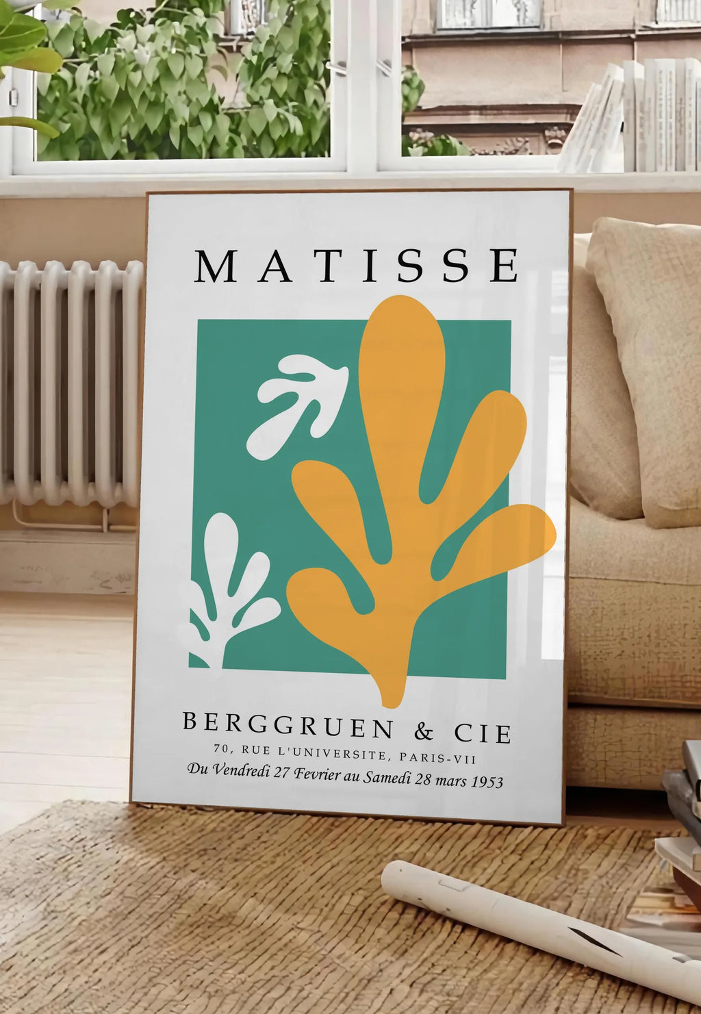 Poster corail Jaune sur Vert en papiers decoupes Matisse sur fond colore, posee au sol dans un salon parisien, devant une grande fenetre donnant sur un immeuble haussmannien, entre un ficus et un canape creme