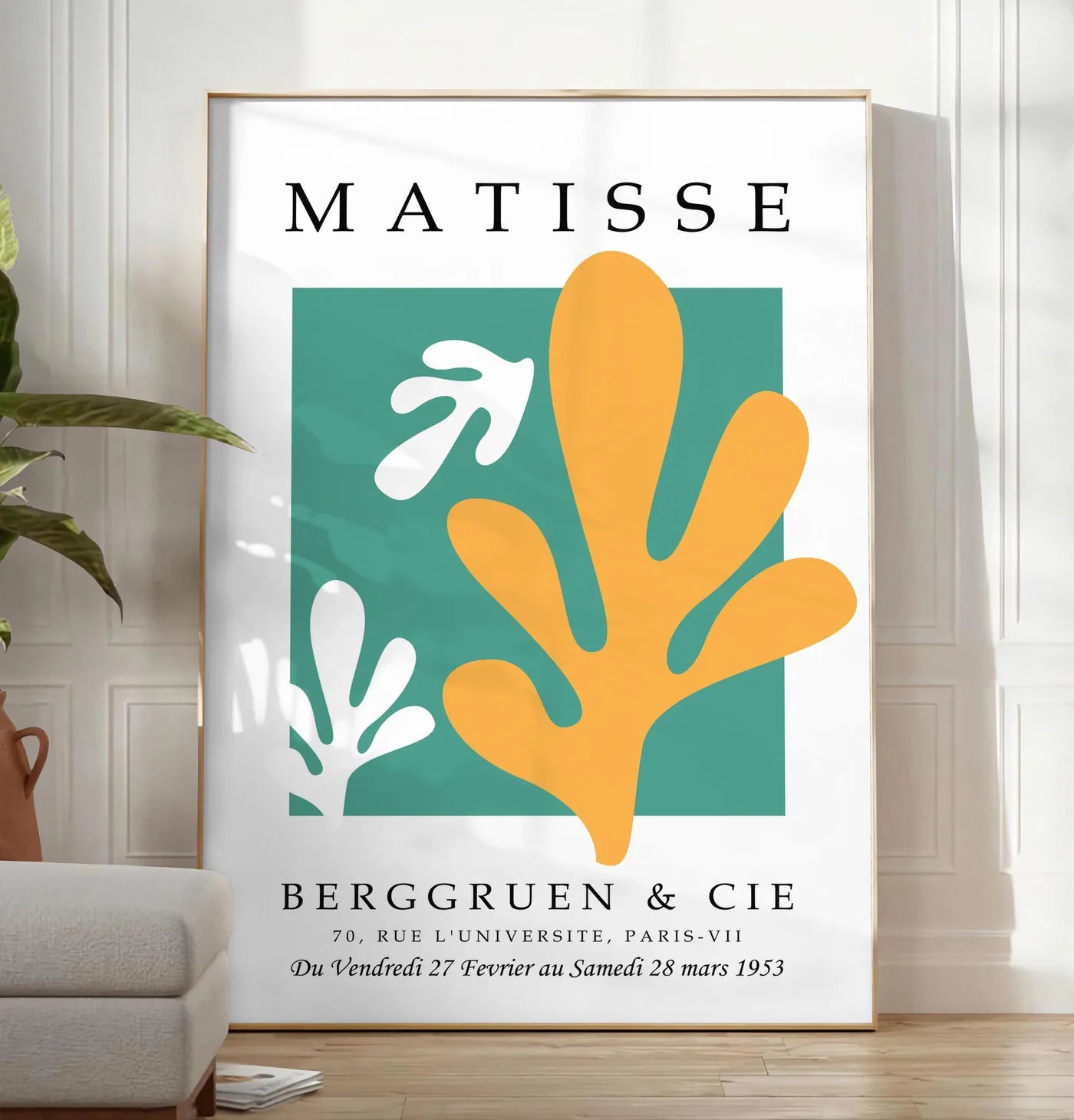 Reproduction corail Jaune sur Vert en papiers decoupes Matisse sur fond colore, posee au sol dans un salon minimaliste clair, a cote d'un canape beige et d'une plante verte, sur un parquet clair