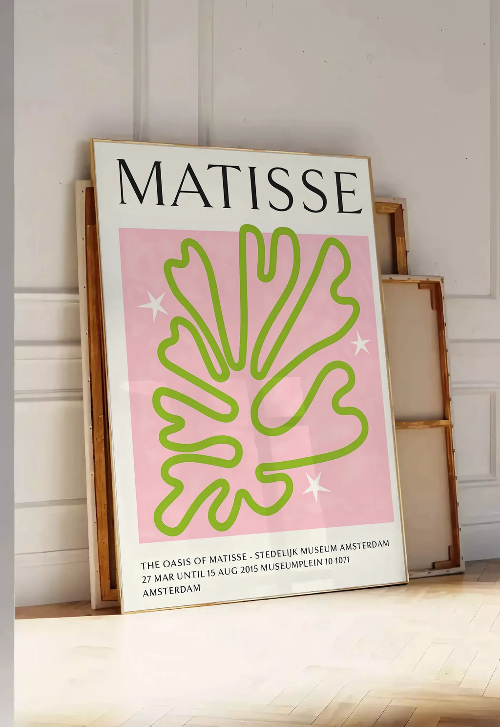 Tirage encadrable corail Vert Oasis en papiers decoupes Matisse sur fond colore, posee au sol dans une entree lumineuse, contre un mur a panneaux blancs, a cote de chassis en bois empiles