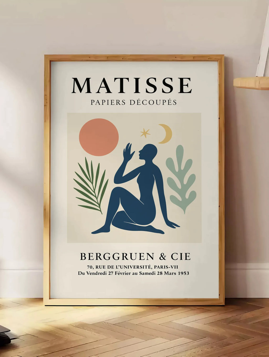 Estampe femme bleue avec lune croissant et etoile, posee au sol dans un coin salon, sur un parquet a chevrons, pres d'une table d'appoint en chene chargee de livres