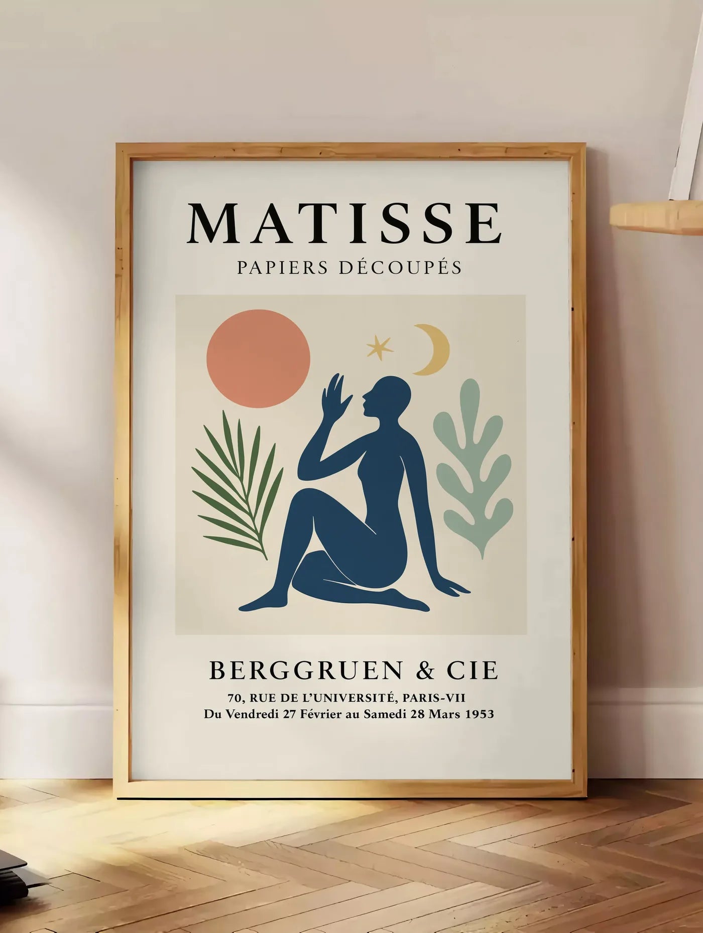 Estampe femme bleue avec lune croissant et etoile, posee au sol dans un coin salon, sur un parquet a chevrons, pres d'une table d'appoint en chene chargee de livres