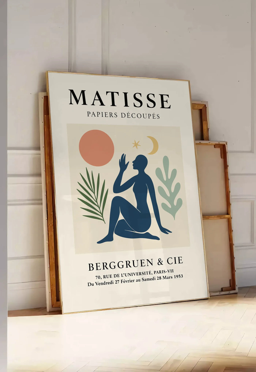 Tirage encadrable femme bleue avec lune croissant et etoile, posee au sol dans une entree lumineuse, contre un mur a panneaux blancs, a cote de chassis en bois empiles