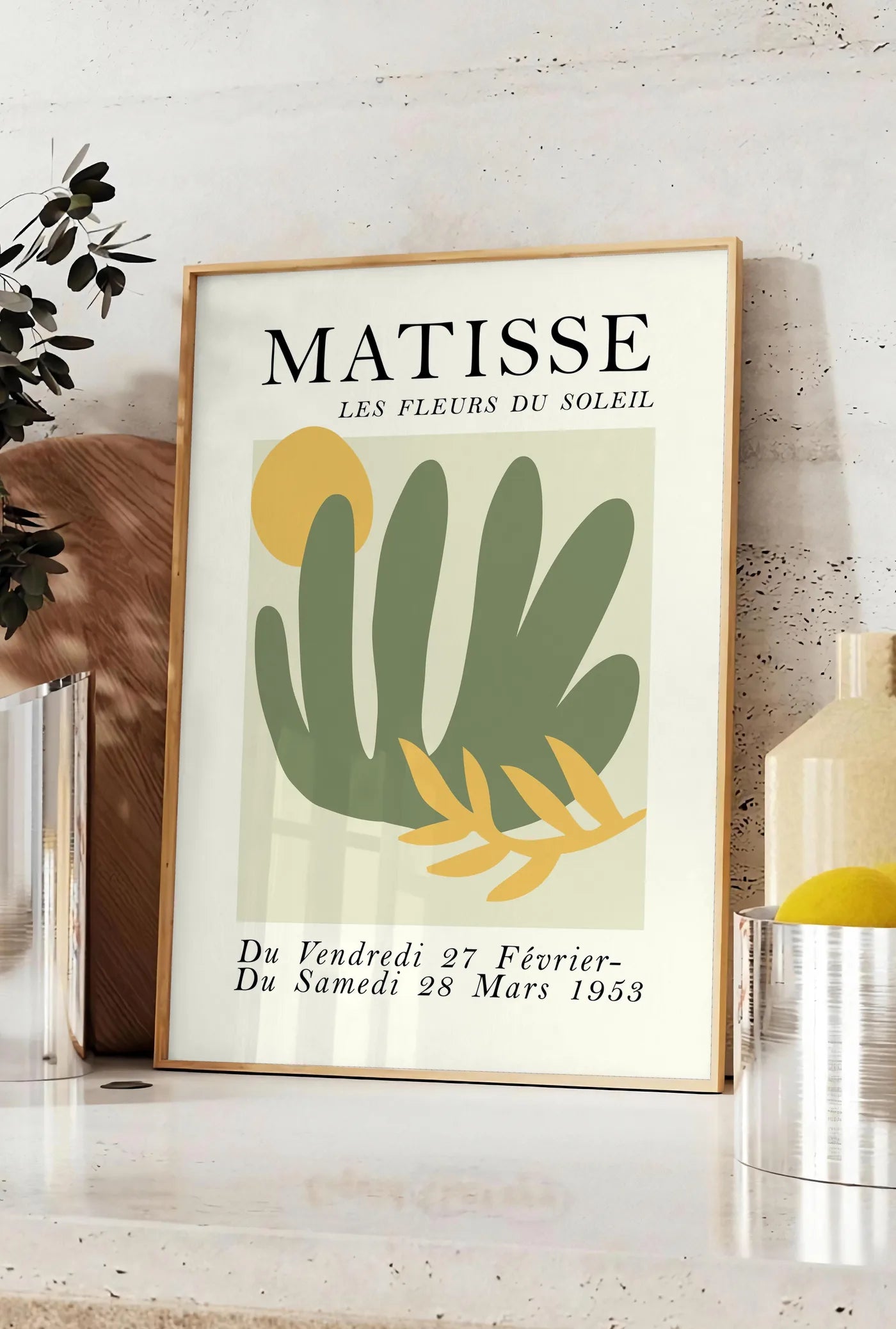 Affiche les Fleurs du Soleil en papiers decoupes Matisse sur fond colore, posee sur un plan de travail de cuisine en pierre claire, entre une branche d'eucalyptus en vase et un bocal de citrons