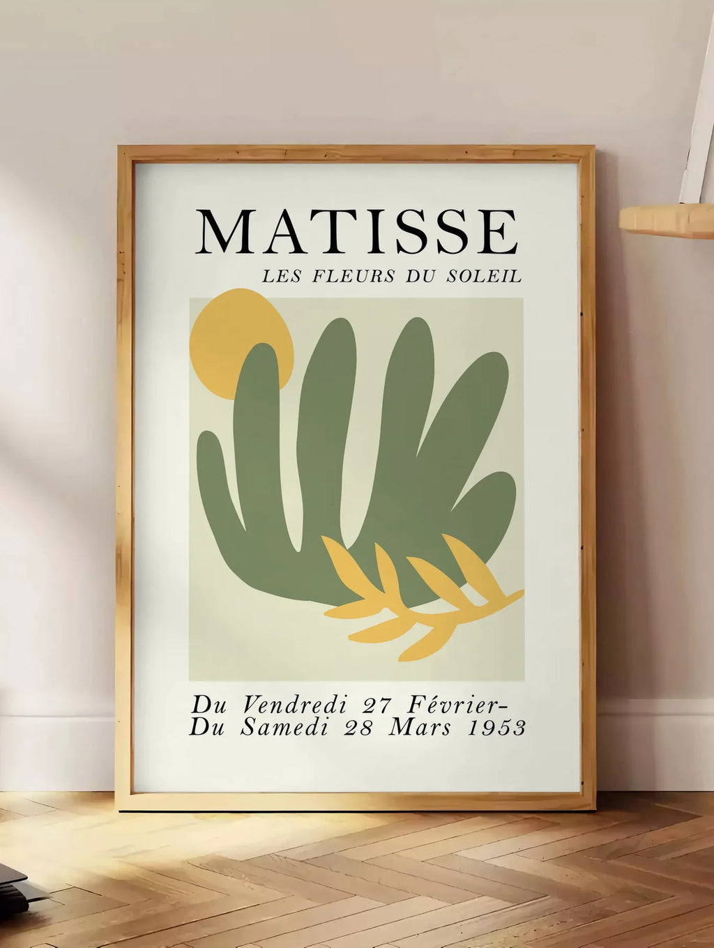 Estampe les Fleurs du Soleil en papiers decoupes Matisse sur fond colore, posee au sol dans un coin salon, sur un parquet a chevrons, pres d'une table d'appoint en chene chargee de livres