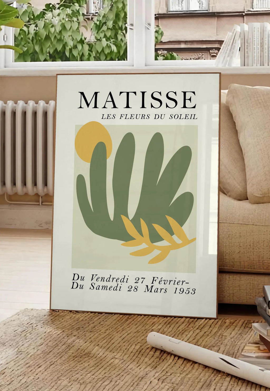Poster les Fleurs du Soleil en papiers decoupes Matisse sur fond colore, posee au sol dans un salon parisien, devant une grande fenetre donnant sur un immeuble haussmannien, entre un ficus et un canape creme
