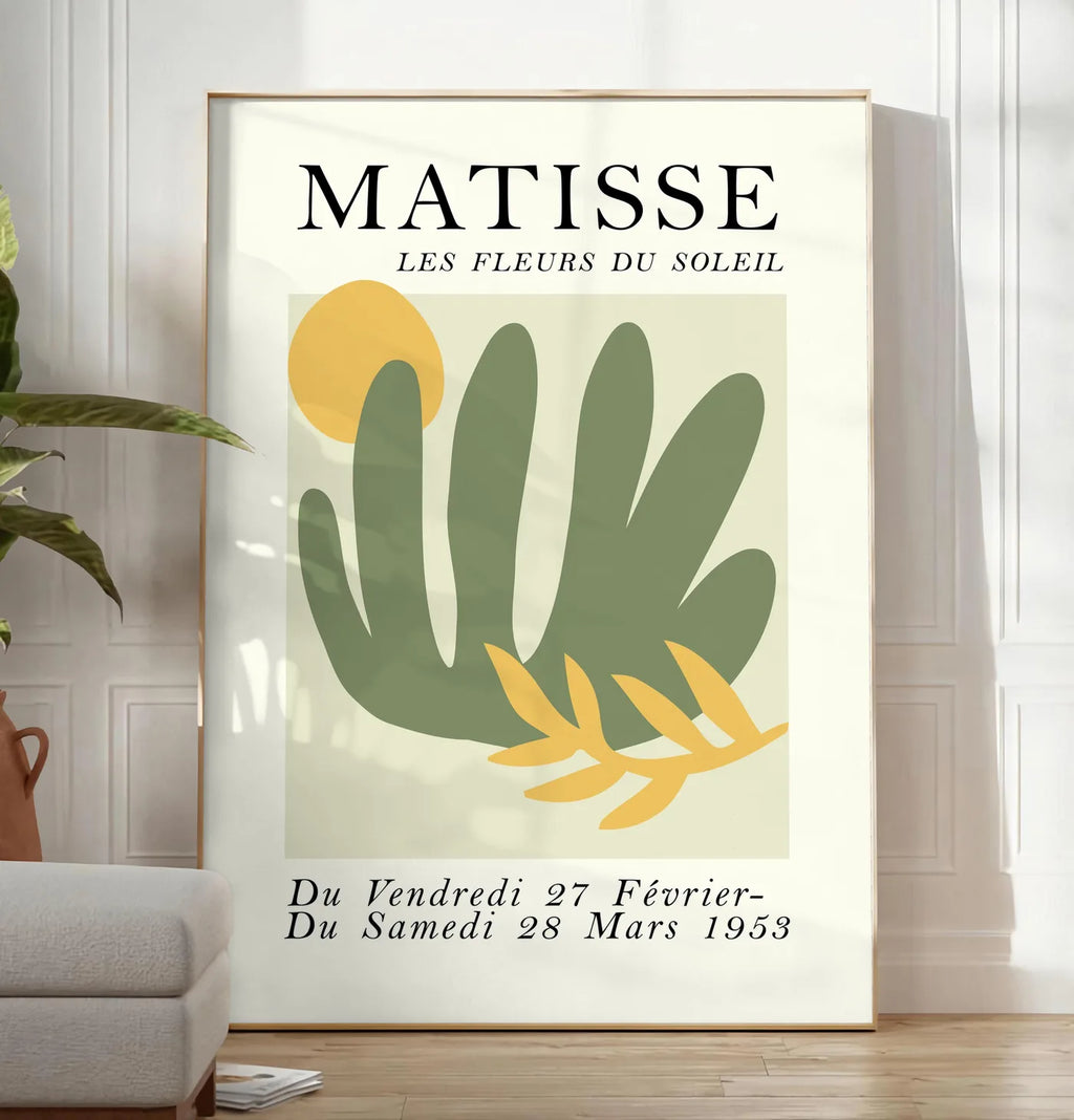 Reproduction les Fleurs du Soleil en papiers decoupes Matisse sur fond colore, posee au sol dans un salon minimaliste clair, a cote d'un canape beige et d'une plante verte, sur un parquet clair
