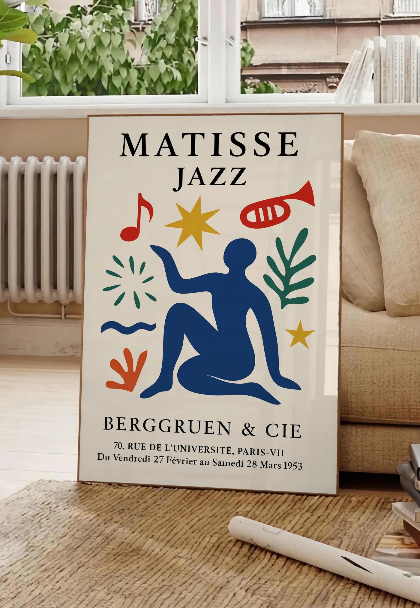 Poster affiche Matisse Jazz, posee au sol dans un salon parisien, devant une grande fenetre donnant sur un immeuble haussmannien, entre un ficus et un canape creme