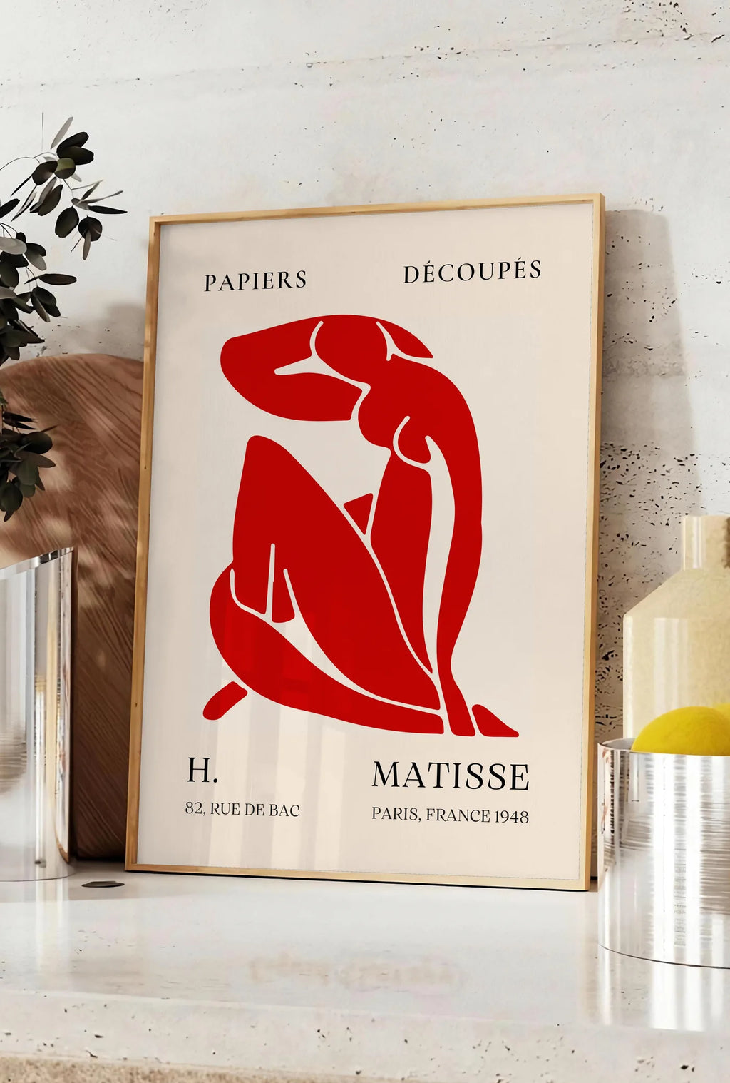 Affiche affiche Matisse Papiers Decoupes, posee sur un plan de travail de cuisine en pierre claire, entre une branche d'eucalyptus en vase et un bocal de citrons
