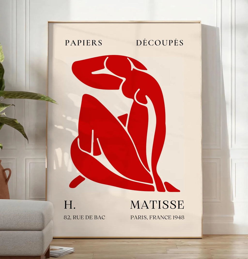 Reproduction affiche Matisse Papiers Decoupes, posee au sol dans un salon minimaliste clair, a cote d'un canape beige et d'une plante verte, sur un parquet clair