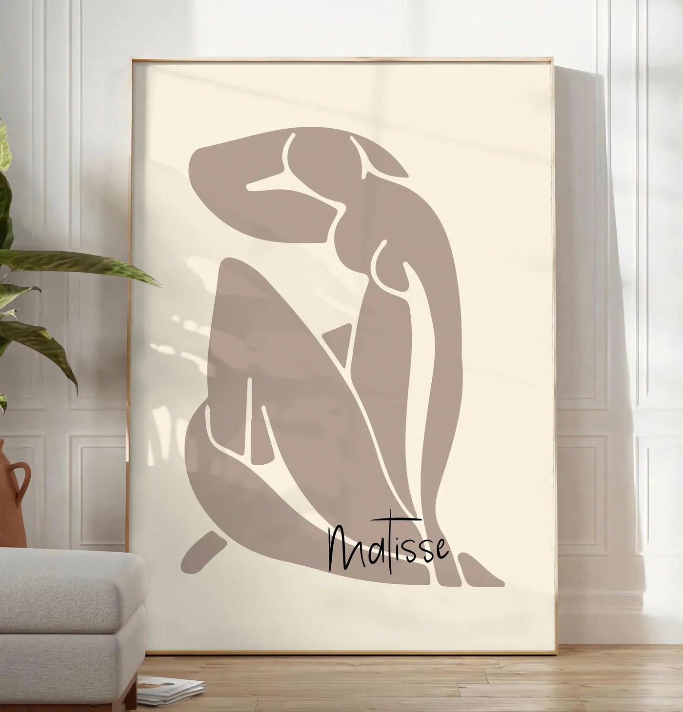 Reproduction nu assis taupe au trait blanc sur fond creme, posee au sol dans un salon minimaliste clair, a cote d'un canape beige et d'une plante verte, sur un parquet clair