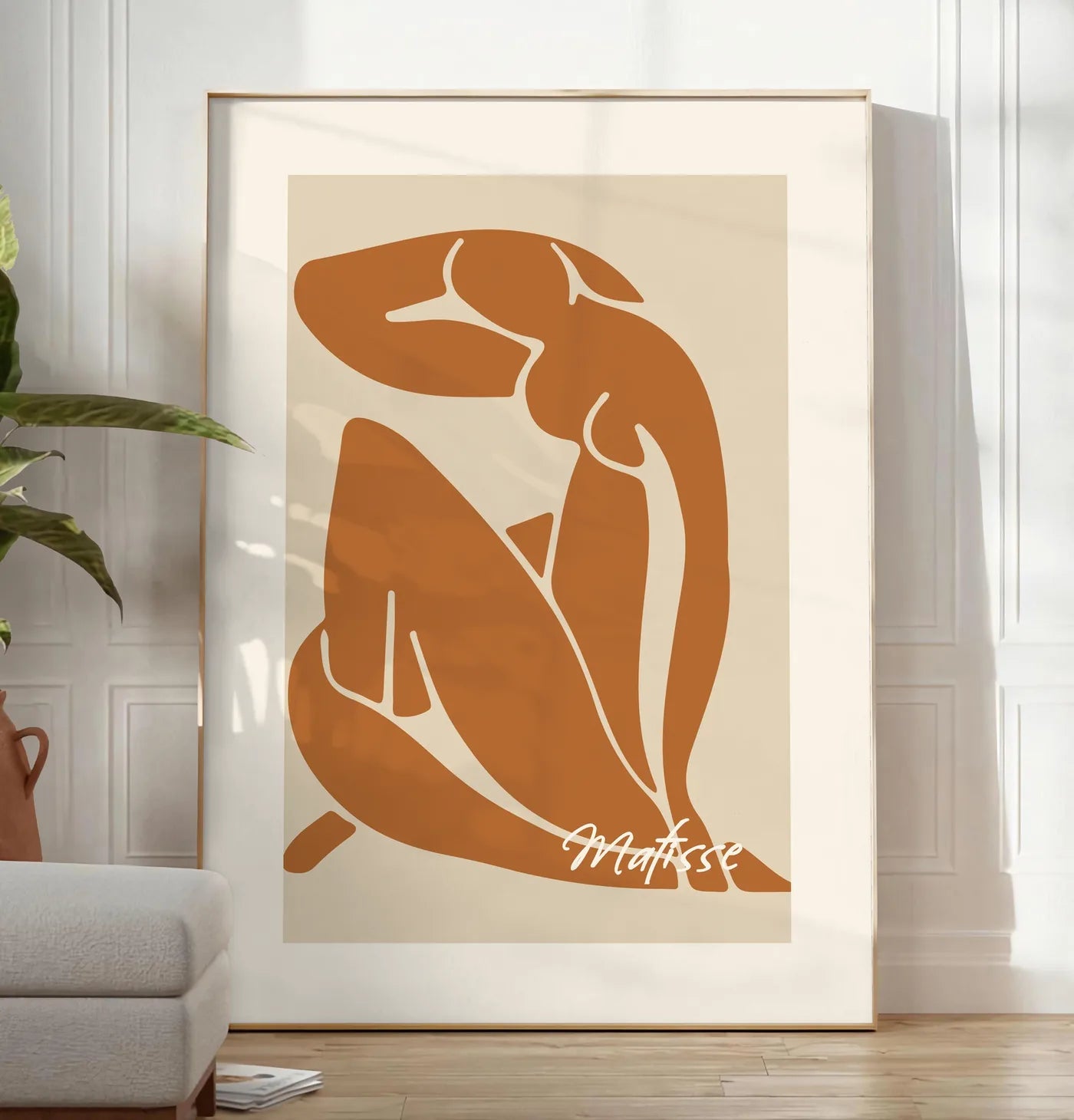 Reproduction affiche Matisse, posee au sol dans un salon minimaliste clair, a cote d'un canape beige et d'une plante verte, sur un parquet clair