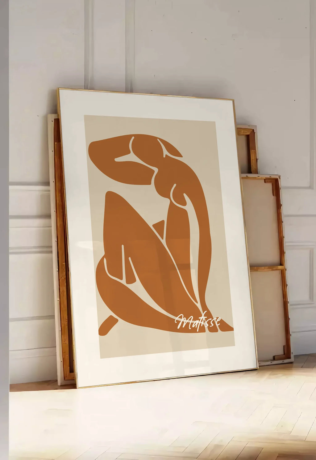 Tirage encadrable affiche Matisse, posee au sol dans une entree lumineuse, contre un mur a panneaux blancs, a cote de chassis en bois empiles