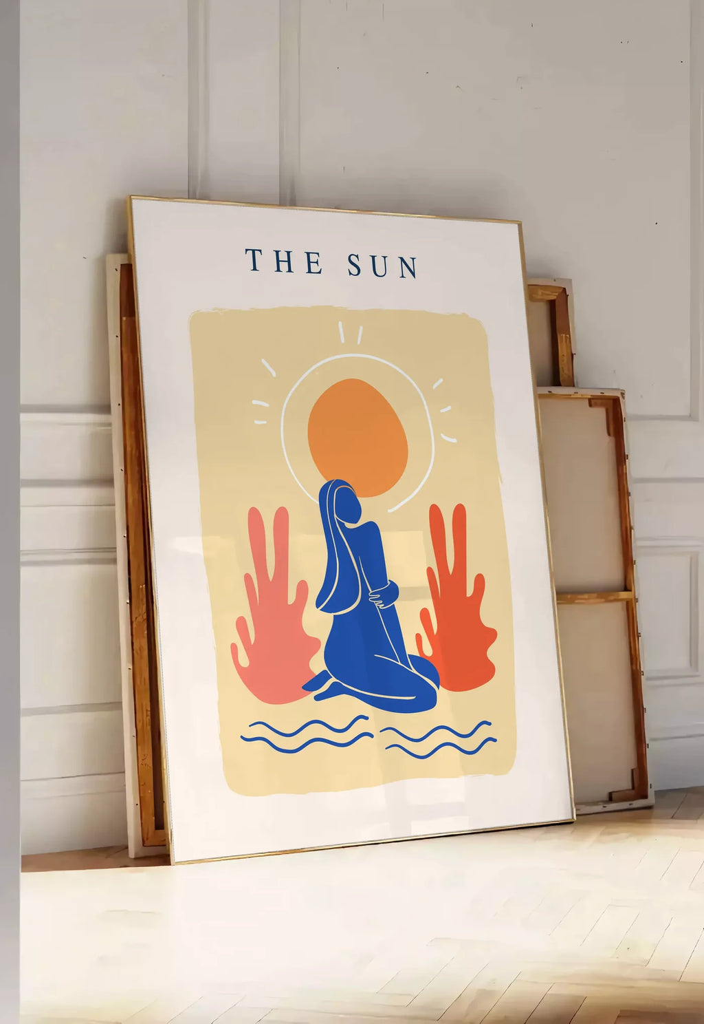 Tirage encadrable femme bleue agenouillee devant un soleil orange et des plantes corail, posee au sol dans une entree lumineuse, contre un mur a panneaux blancs, a cote de chassis en bois empiles
