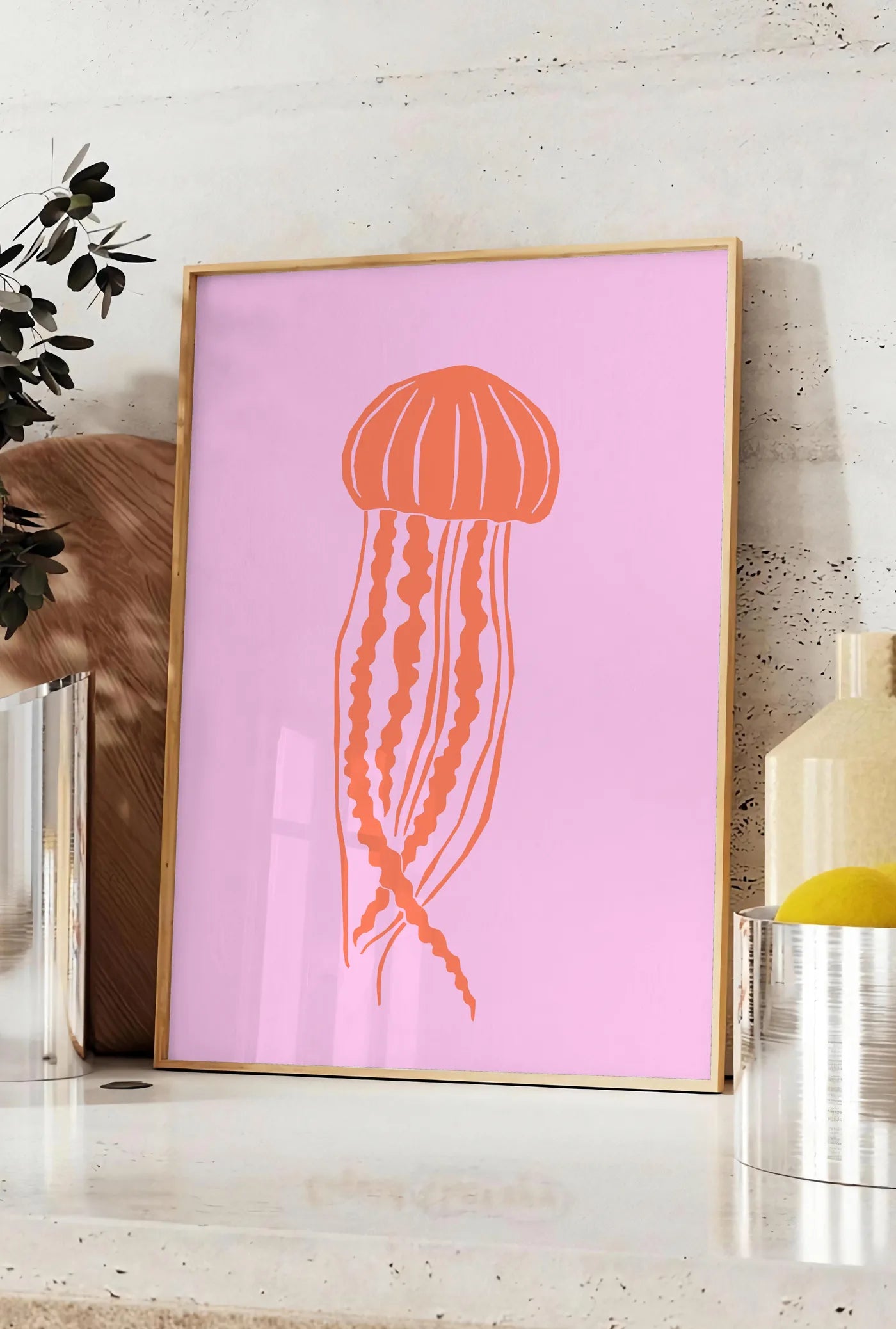 Affiche affiche meduse minimaliste, posee sur un plan de travail de cuisine en pierre claire, entre une branche d'eucalyptus en vase et un bocal de citrons