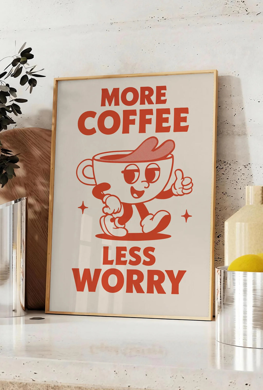 Affiche affiche cuisine cafe More Coffee Less Worry, posee sur un plan de travail de cuisine en pierre claire, entre une branche d'eucalyptus en vase et un bocal de citrons