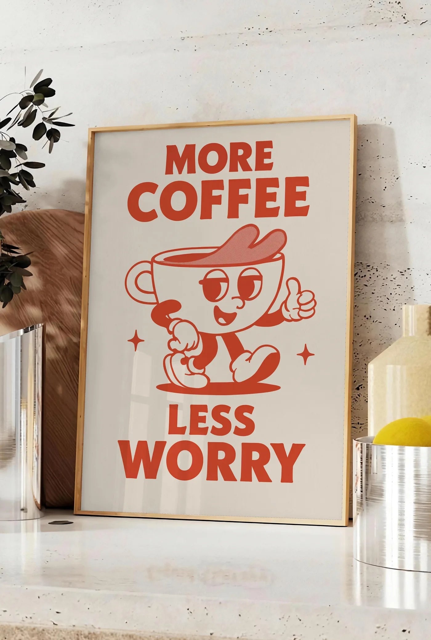 Affiche affiche cuisine cafe More Coffee Less Worry, posee sur un plan de travail de cuisine en pierre claire, entre une branche d'eucalyptus en vase et un bocal de citrons