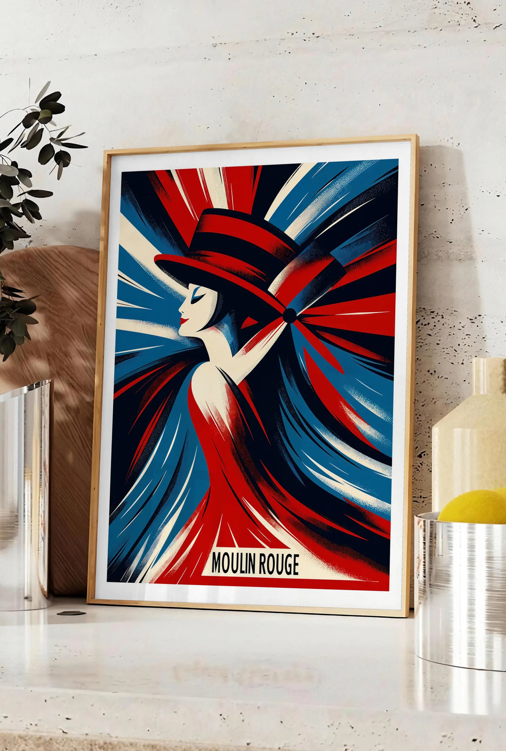 Affiche affiche Moulin Rouge Art Deco, posee sur un plan de travail de cuisine en pierre claire, entre une branche d'eucalyptus en vase et un bocal de citrons