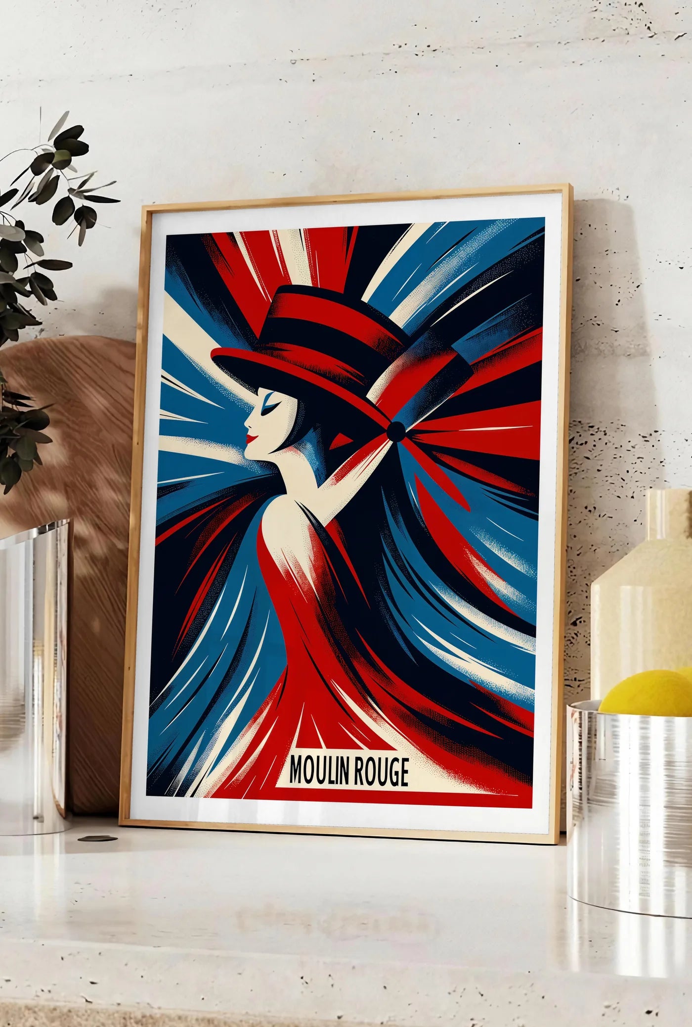 Affiche affiche Moulin Rouge Art Deco, posee sur un plan de travail de cuisine en pierre claire, entre une branche d'eucalyptus en vase et un bocal de citrons