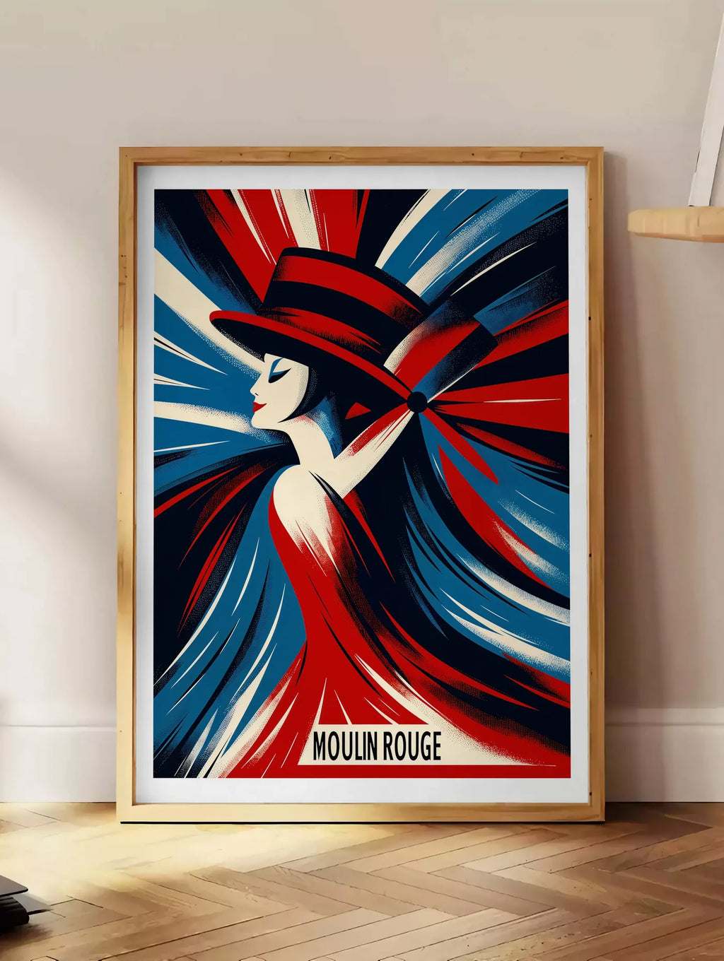 Estampe affiche Moulin Rouge Art Deco, posee au sol dans un coin salon, sur un parquet a chevrons, pres d'une table d'appoint en chene chargee de livres