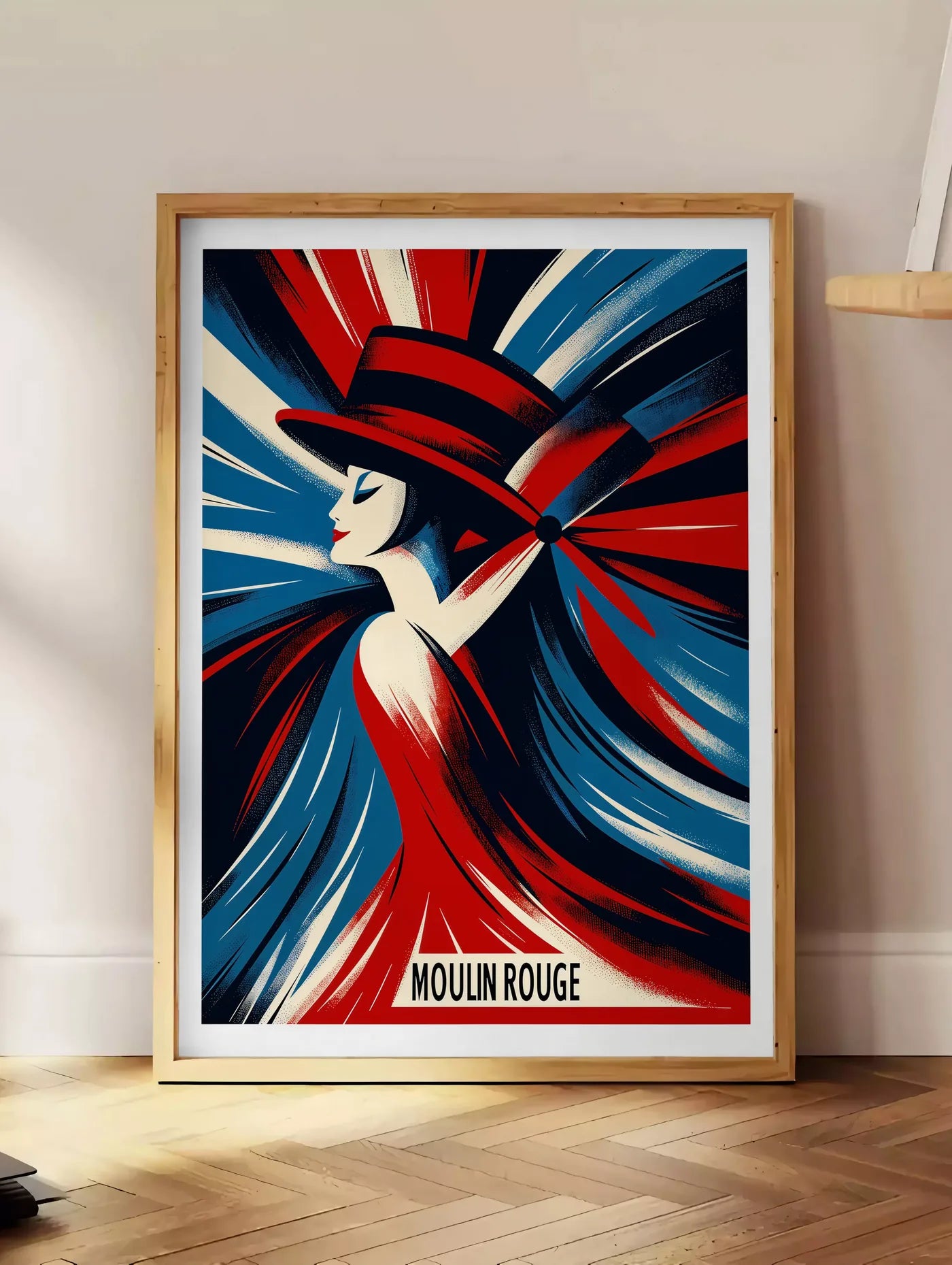 Estampe affiche Moulin Rouge Art Deco, posee au sol dans un coin salon, sur un parquet a chevrons, pres d'une table d'appoint en chene chargee de livres