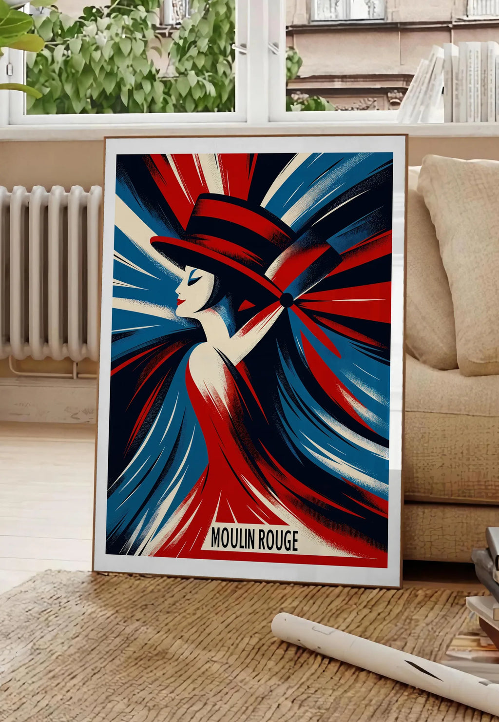 Poster affiche Moulin Rouge Art Deco, posee au sol dans un salon parisien, devant une grande fenetre donnant sur un immeuble haussmannien, entre un ficus et un canape creme