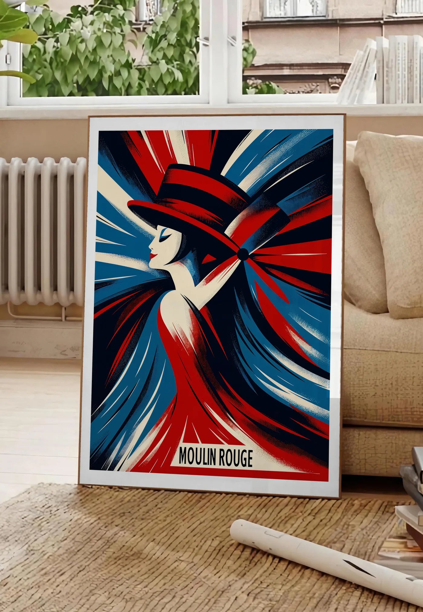 Poster affiche Moulin Rouge Art Deco, posee au sol dans un salon parisien, devant une grande fenetre donnant sur un immeuble haussmannien, entre un ficus et un canape creme