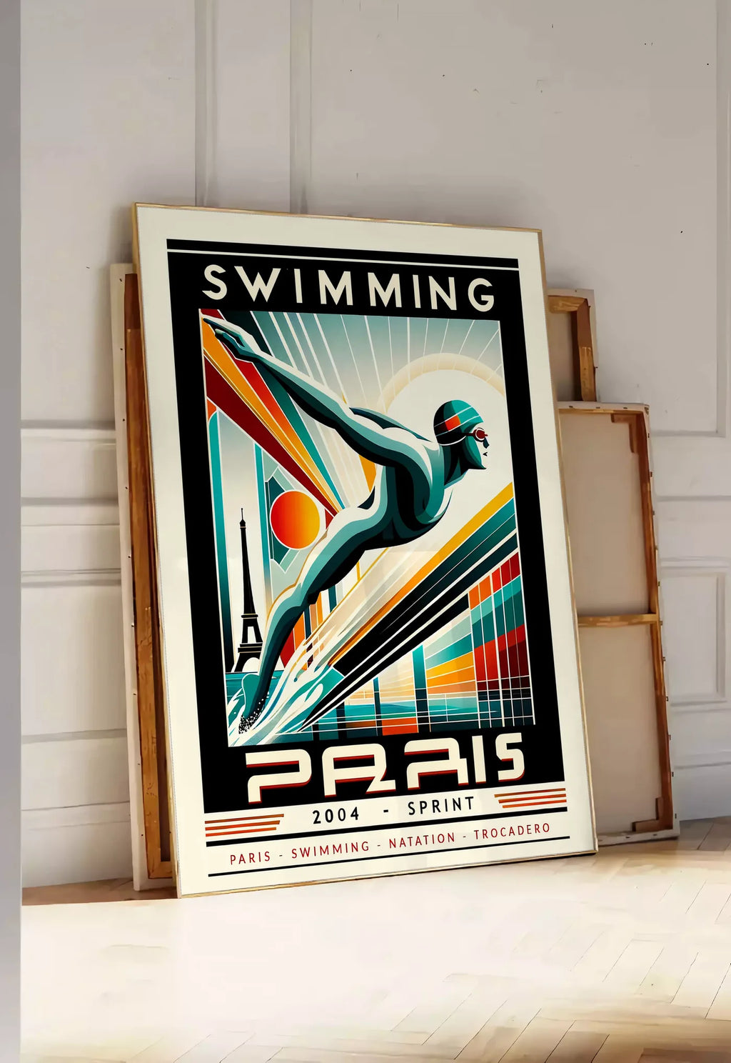 Tirage encadrable affiche natation Paris Sprint art deco, posee au sol dans une entree lumineuse, contre un mur a panneaux blancs, a cote de chassis en bois empiles