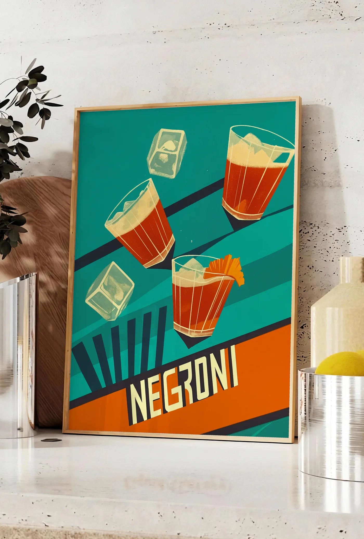 Affiche affiche cocktail Negroni, posee sur un plan de travail de cuisine en pierre claire, entre une branche d'eucalyptus en vase et un bocal de citrons