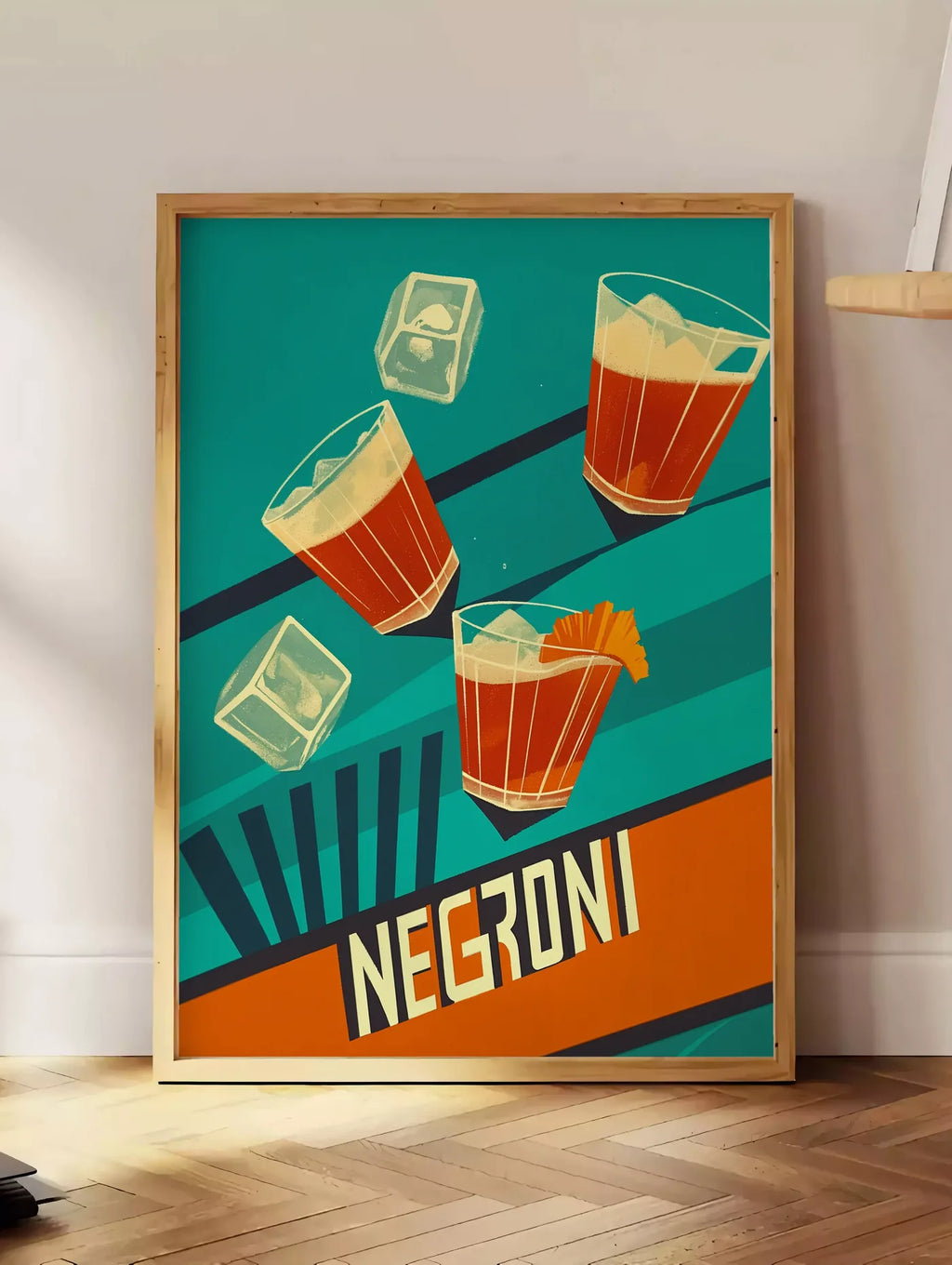 Estampe affiche cocktail Negroni, posee au sol dans un coin salon, sur un parquet a chevrons, pres d'une table d'appoint en chene chargee de livres
