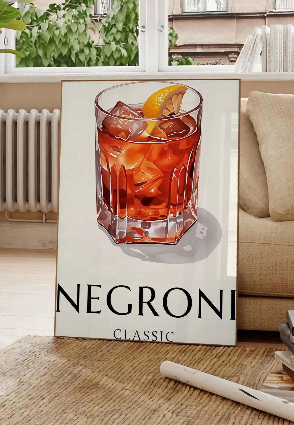 Poster affiche cocktail Negroni, posee au sol dans un salon parisien, devant une grande fenetre donnant sur un immeuble haussmannien, entre un ficus et un canape creme