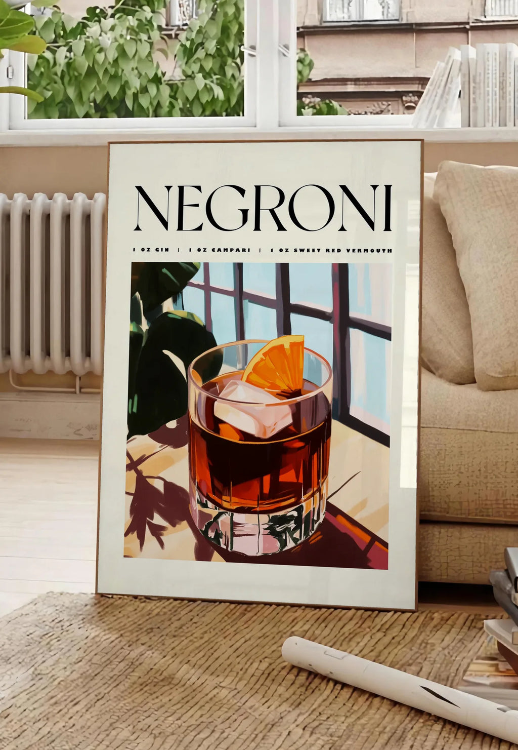 Poster affiche cocktail Negroni, posee au sol dans un salon parisien, devant une grande fenetre donnant sur un immeuble haussmannien, entre un ficus et un canape creme