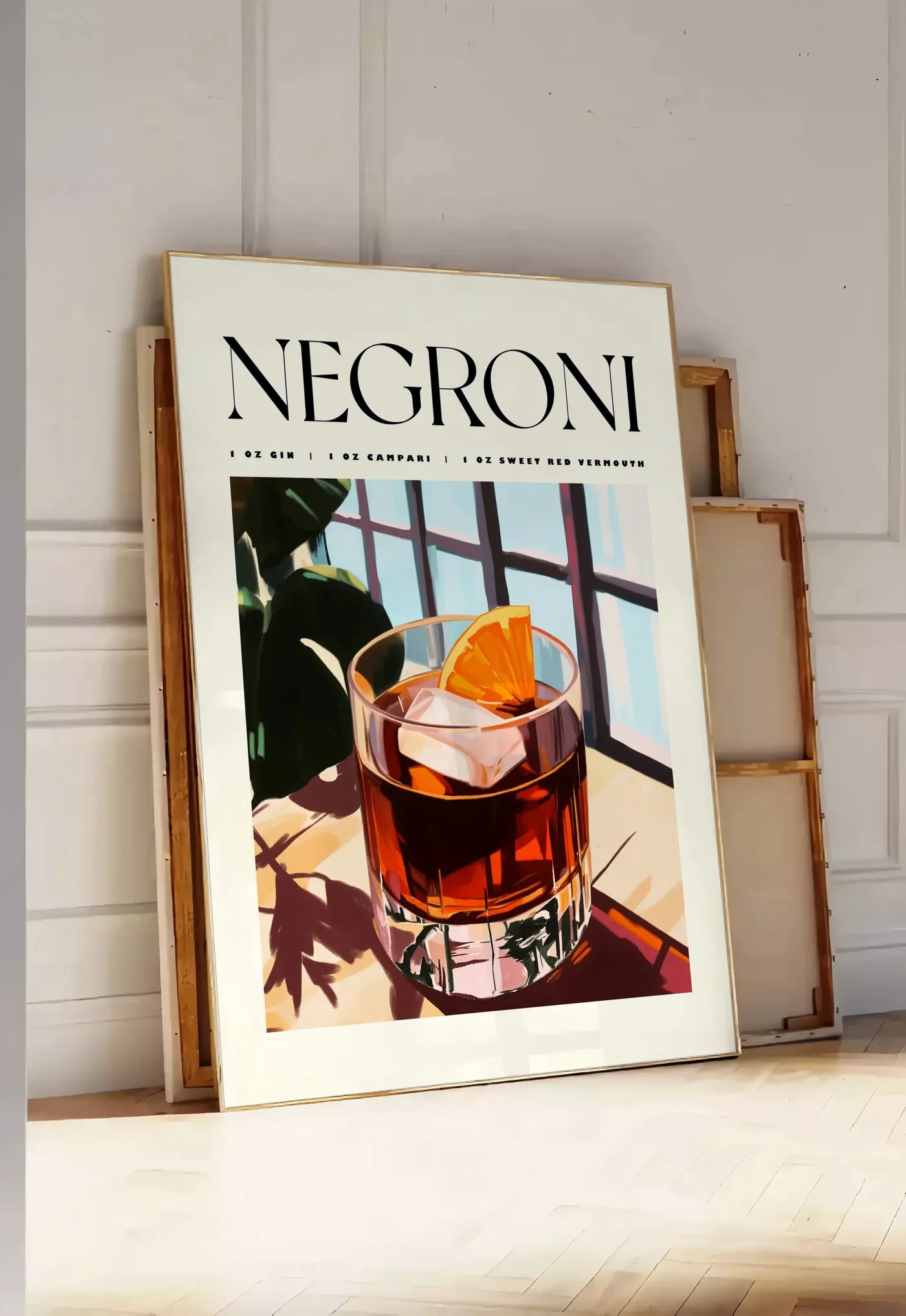Tirage encadrable affiche cocktail Negroni, posee au sol dans une entree lumineuse, contre un mur a panneaux blancs, a cote de chassis en bois empiles