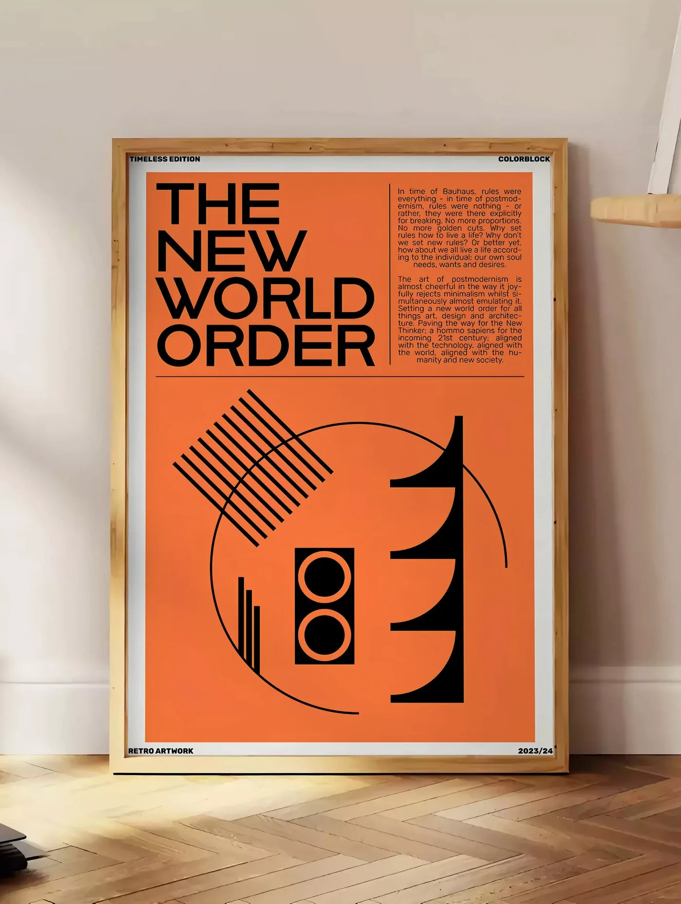 Estampe typographie The New World Order en noir sur orange, posee au sol dans un coin salon, sur un parquet a chevrons, pres d'une table d'appoint en chene chargee de livres