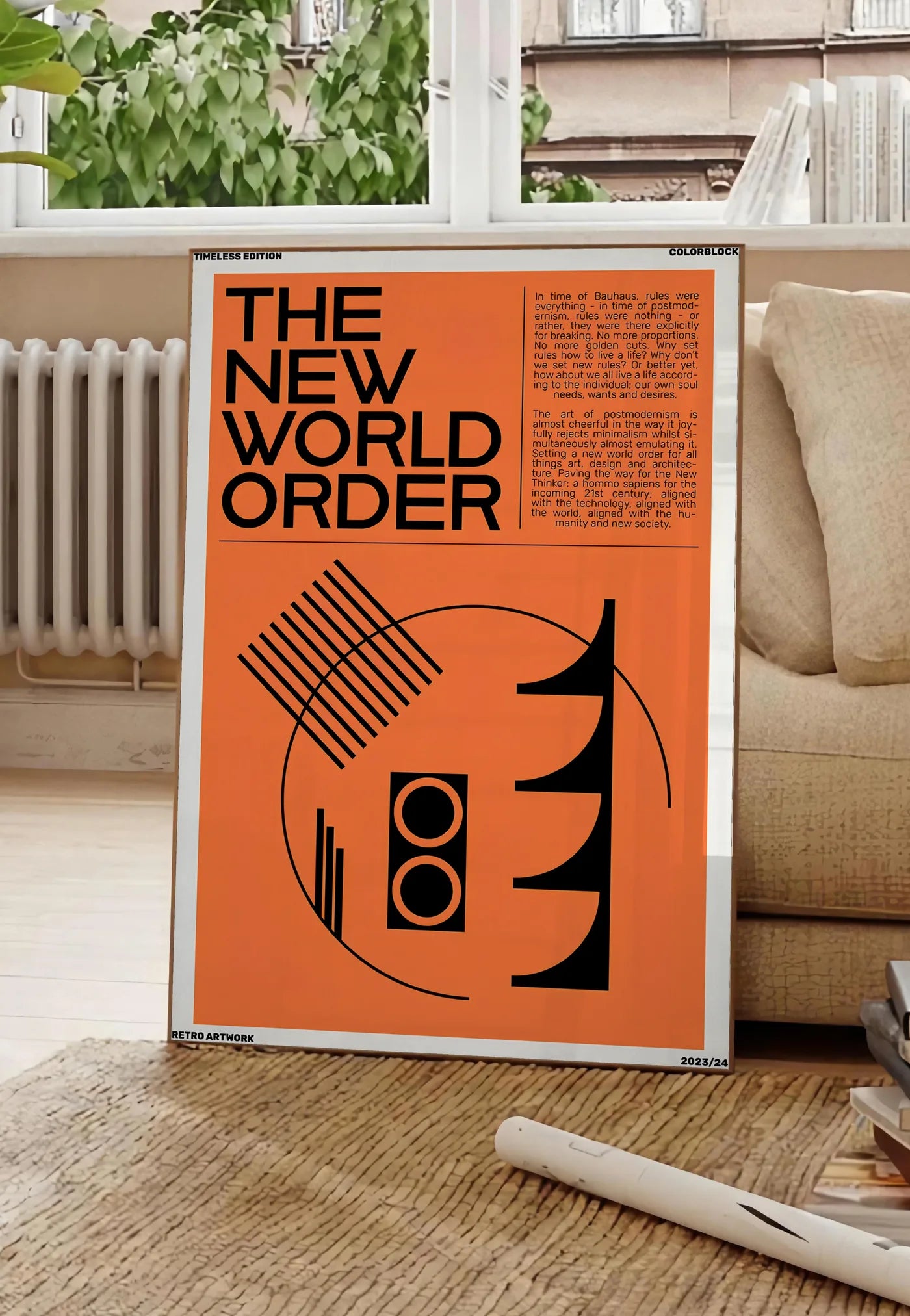 Poster typographie The New World Order en noir sur orange, posee au sol dans un salon parisien, devant une grande fenetre donnant sur un immeuble haussmannien, entre un ficus et un canape creme