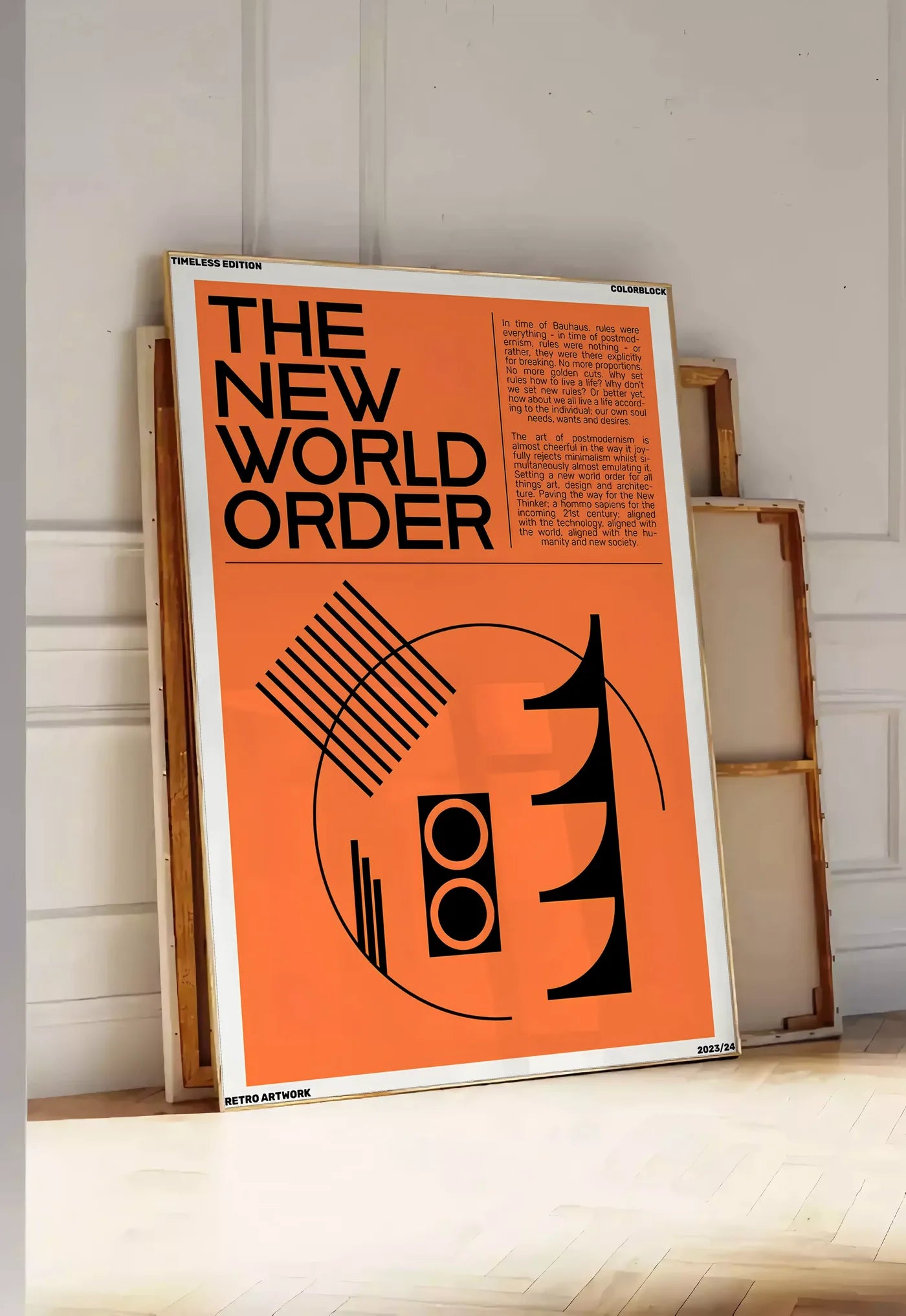 Tirage encadrable typographie The New World Order en noir sur orange, posee au sol dans une entree lumineuse, contre un mur a panneaux blancs, a cote de chassis en bois empiles