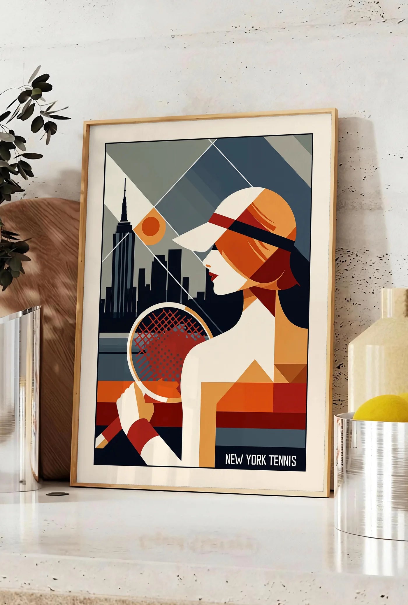 Affiche profil d'une joueuse de tennis en profil, posee sur un plan de travail de cuisine en pierre claire, entre une branche d'eucalyptus en vase et un bocal de citrons