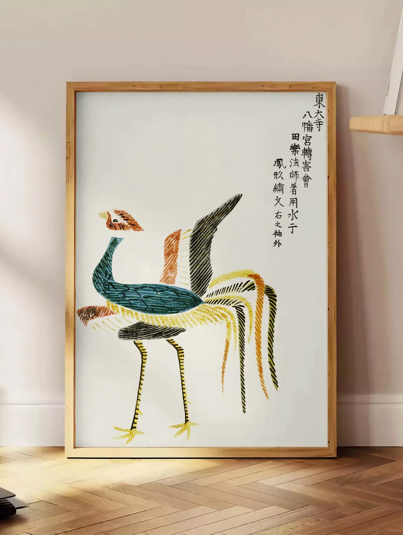 Estampe affiche grues stylisees vintage art japonais, posee au sol dans un coin salon, sur un parquet a chevrons, pres d'une table d'appoint en chene chargee de livres