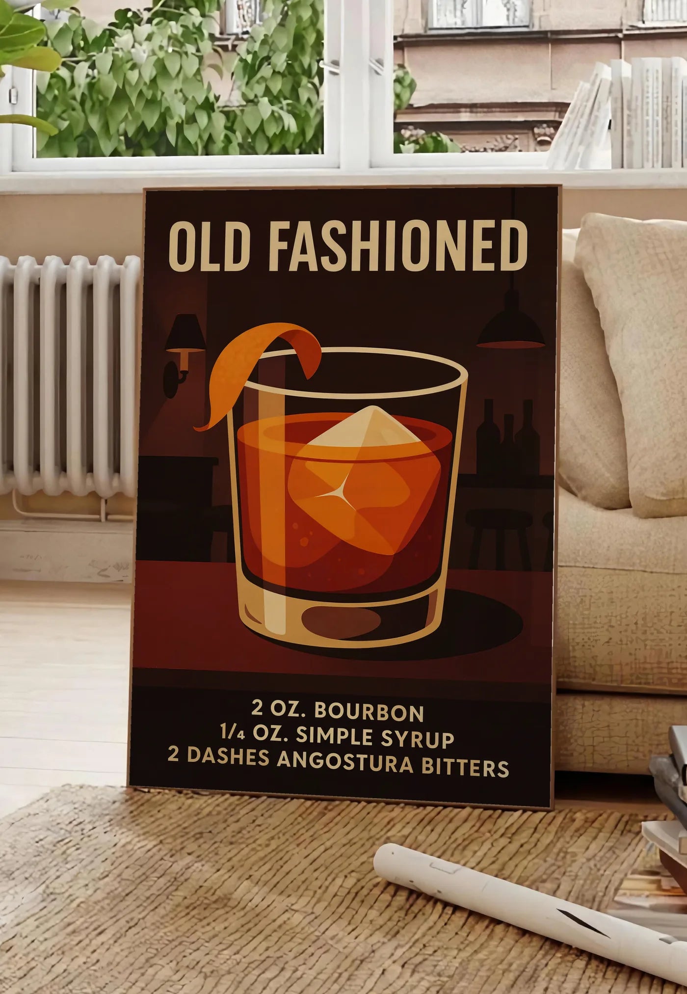 Poster affiche cocktail Old Fashioned, posee au sol dans un salon parisien, devant une grande fenetre donnant sur un immeuble haussmannien, entre un ficus et un canape creme