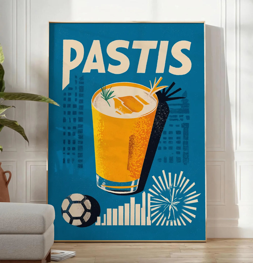 Reproduction affiche cocktail Pastis Marseille, posee au sol dans un salon minimaliste clair, a cote d'un canape beige et d'une plante verte, sur un parquet clair