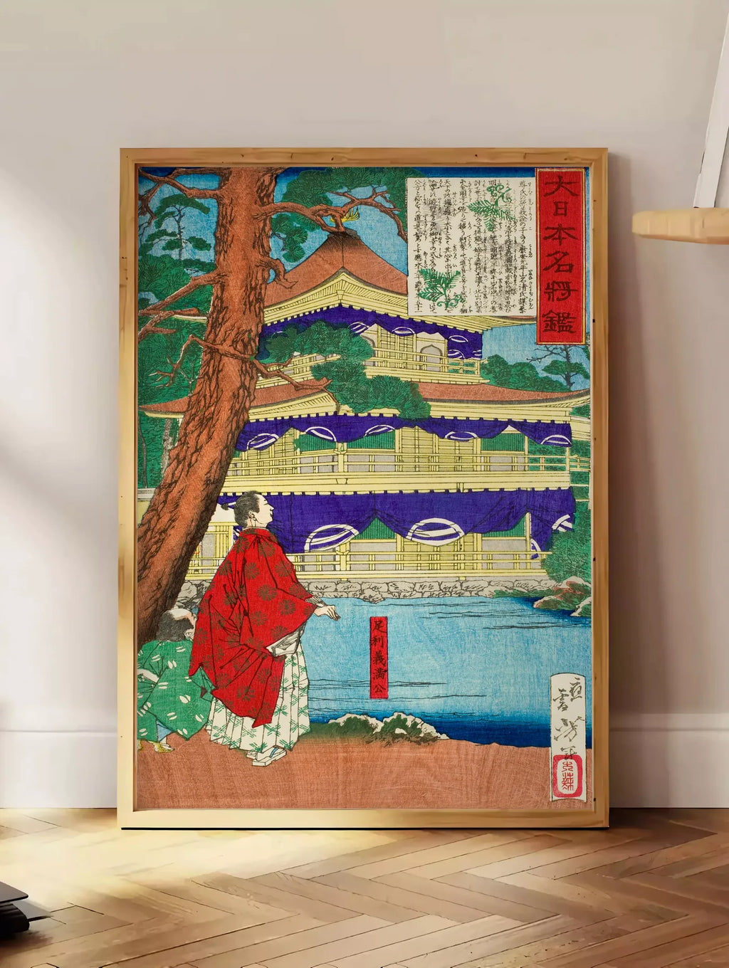 Estampe affiche pavillon dore et samurai art japonais, posee au sol dans un coin salon, sur un parquet a chevrons, pres d'une table d'appoint en chene chargee de livres
