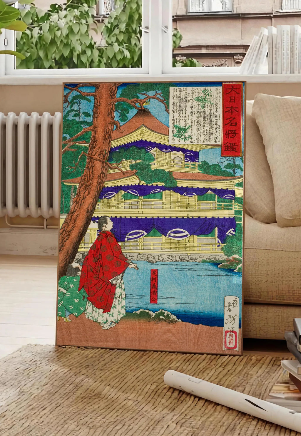 Poster affiche pavillon dore et samurai art japonais, posee au sol dans un salon parisien, devant une grande fenetre donnant sur un immeuble haussmannien, entre un ficus et un canape creme