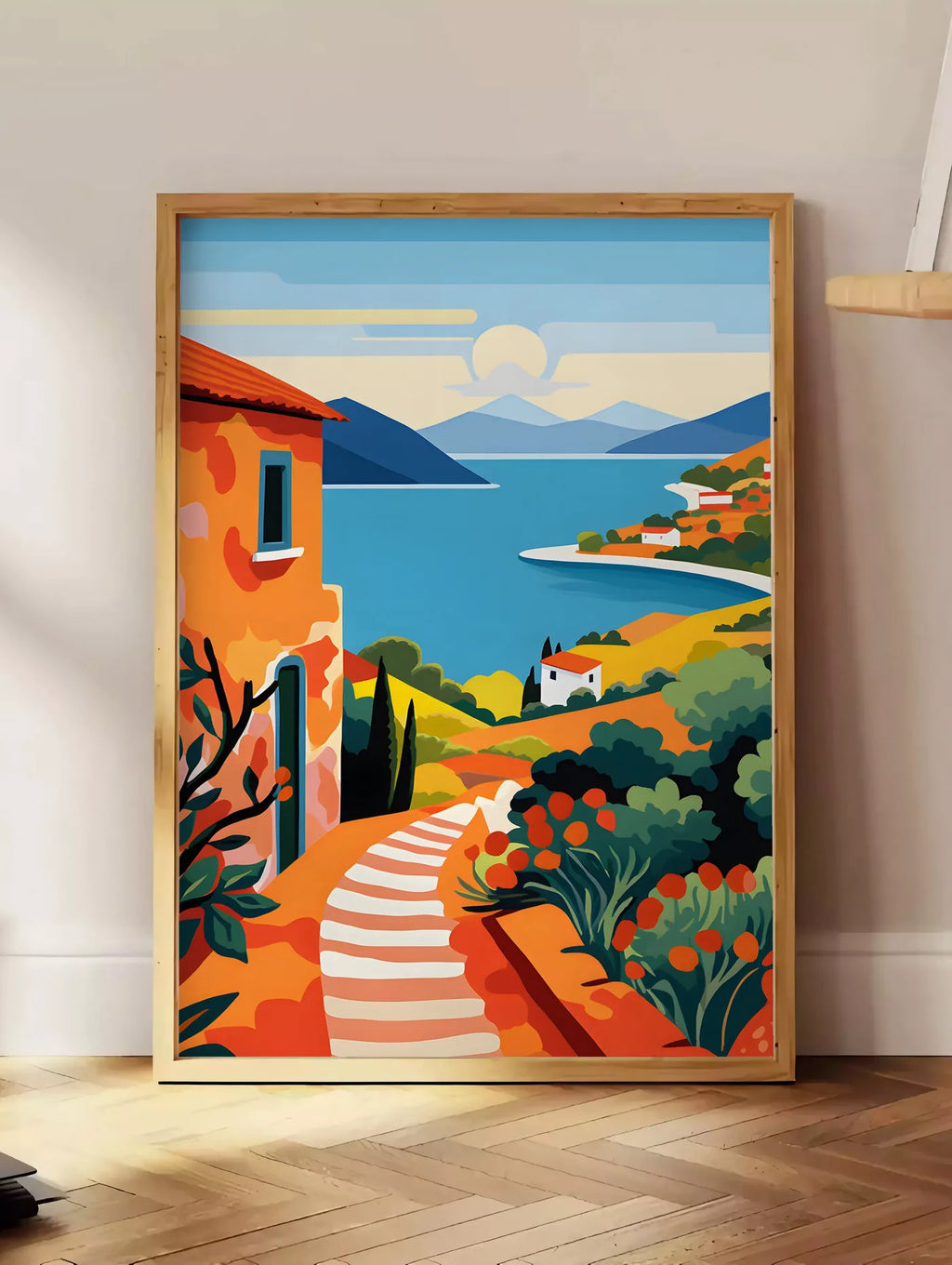 Estampe affiche paysage cote mediterranee, posee au sol dans un coin salon, sur un parquet a chevrons, pres d'une table d'appoint en chene chargee de livres