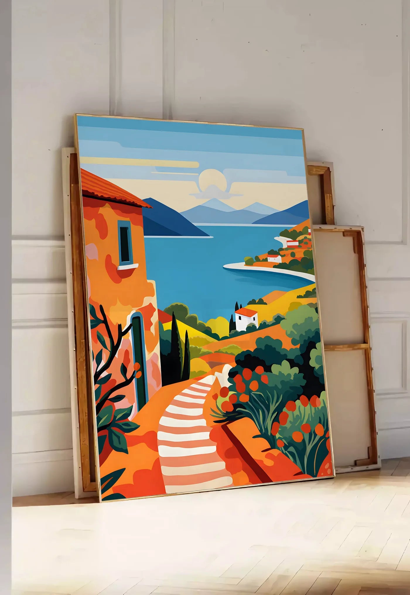 Tirage encadrable affiche paysage cote mediterranee, posee au sol dans une entree lumineuse, contre un mur a panneaux blancs, a cote de chassis en bois empiles