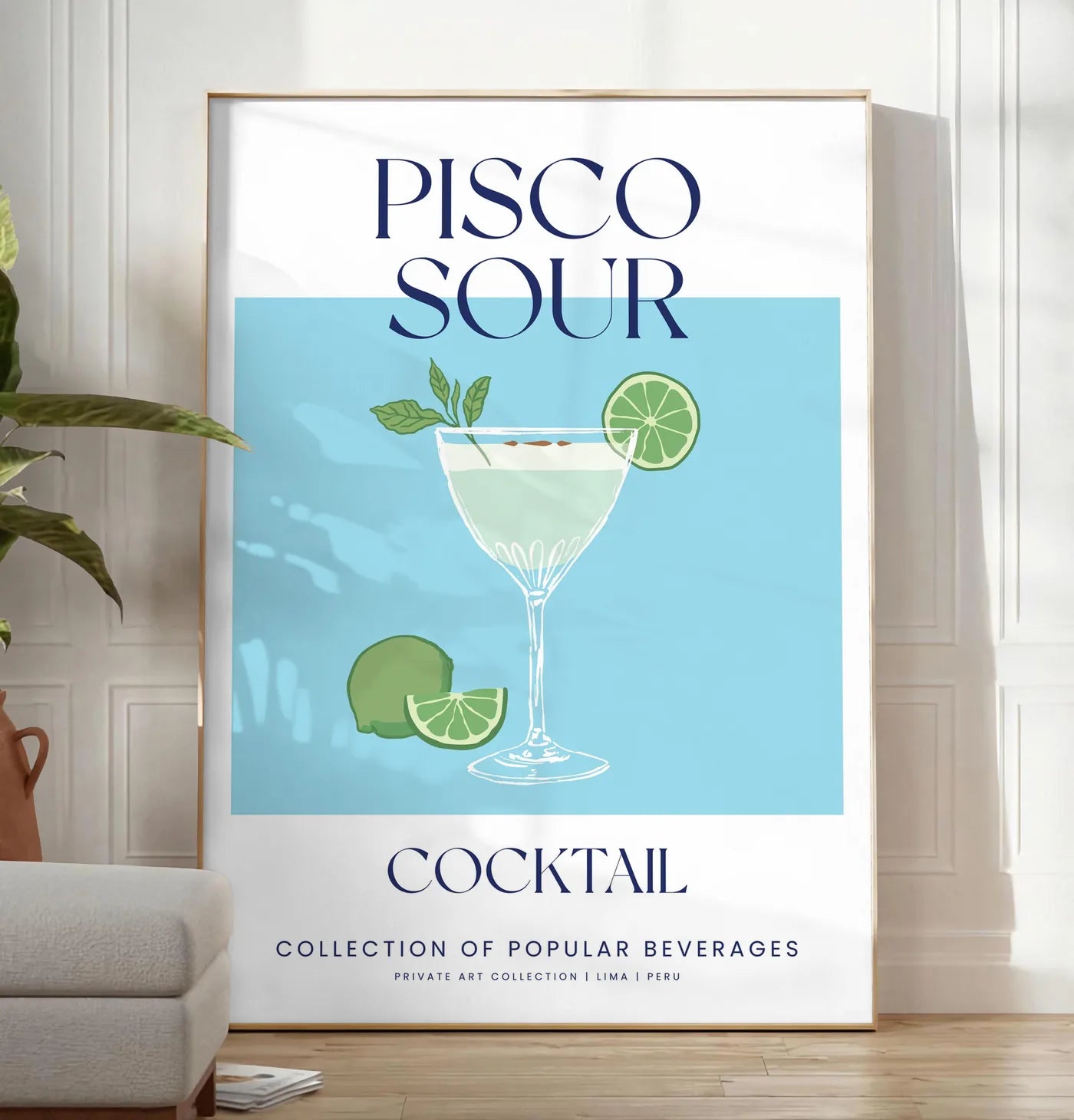 Reproduction affiche cocktail Pisco Sour, posee au sol dans un salon minimaliste clair, a cote d'un canape beige et d'une plante verte, sur un parquet clair