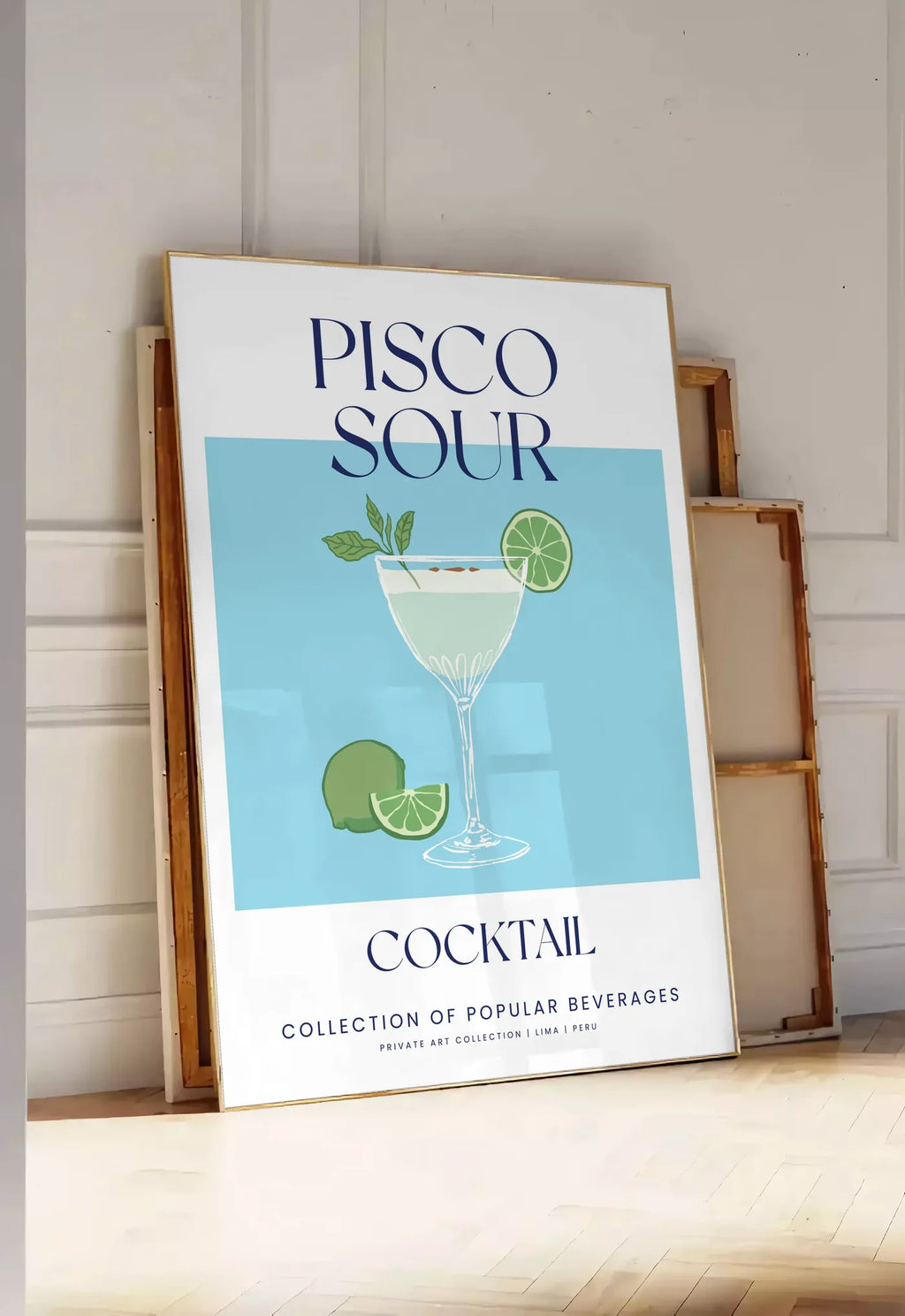 Tirage encadrable affiche cocktail Pisco Sour, posee au sol dans une entree lumineuse, contre un mur a panneaux blancs, a cote de chassis en bois empiles