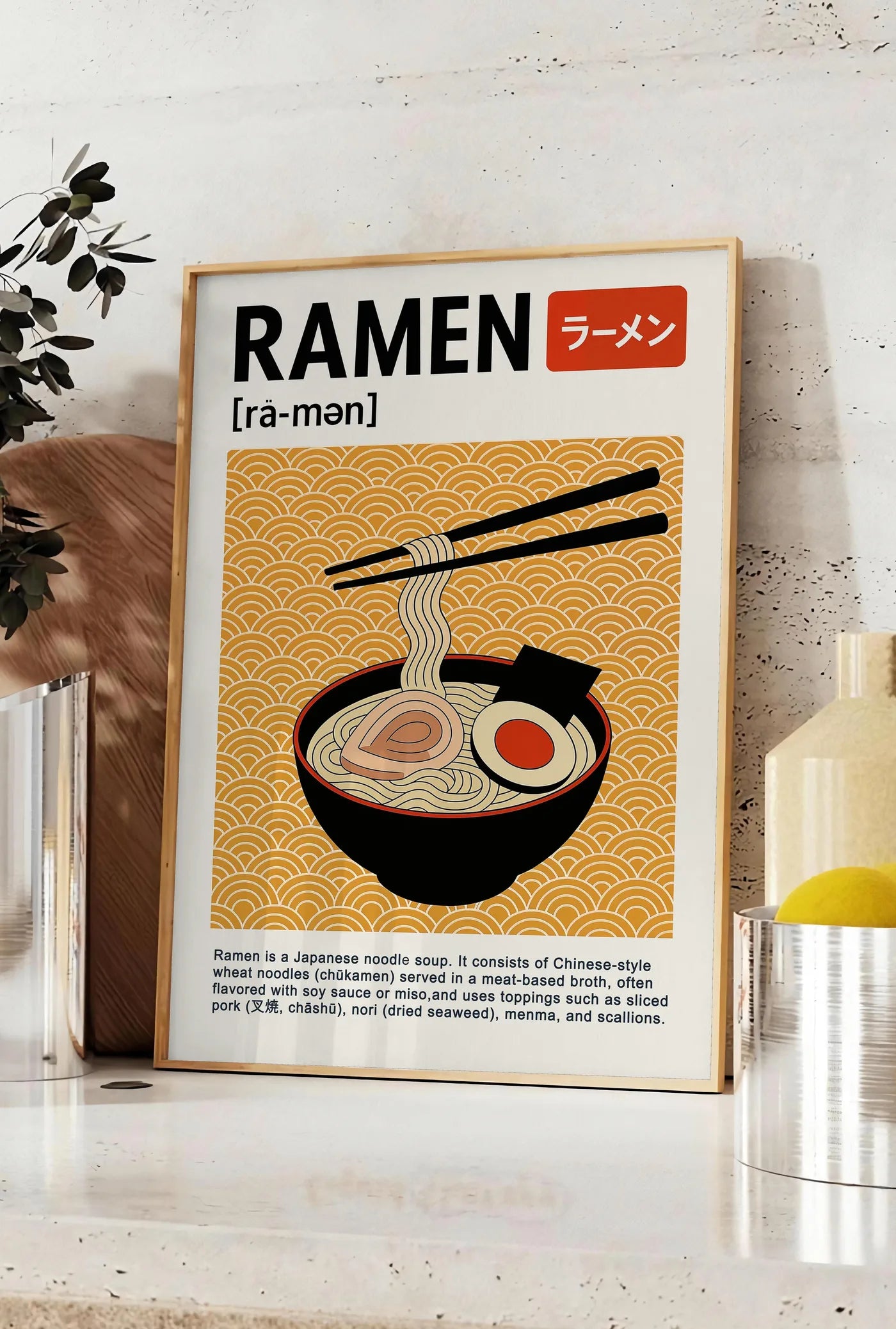 Affiche affiche cuisine ramen japonais, posee sur un plan de travail de cuisine en pierre claire, entre une branche d'eucalyptus en vase et un bocal de citrons